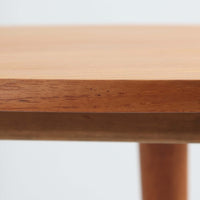 デンマークの巨匠Hans J. Wegner（ハンス・J・ウェグナー）がAndreas Tuck社のためにデザインした「AT8」円形センターテーブルです。チーク材による滑らかな天板と、3本脚の軽やかな構造が特徴で、美しくテーパーのついた脚部が全体に上品な印象を与えます。脚は木製のねじ込み構造になっており、工具を使わずに着脱が可能です。こうしたディテールにもビンテージ期ならではの職人技が感じられます。脚部までチーク材が使用された希少なタイプで、素材の統一感と温かみのある質感が際立ちます。ウェグナーらしいシンプルで機能的な造形と、経年により深みを増したチークの風合いが融合し、リビング空間に上質な北欧のぬくもりを添える一台です。