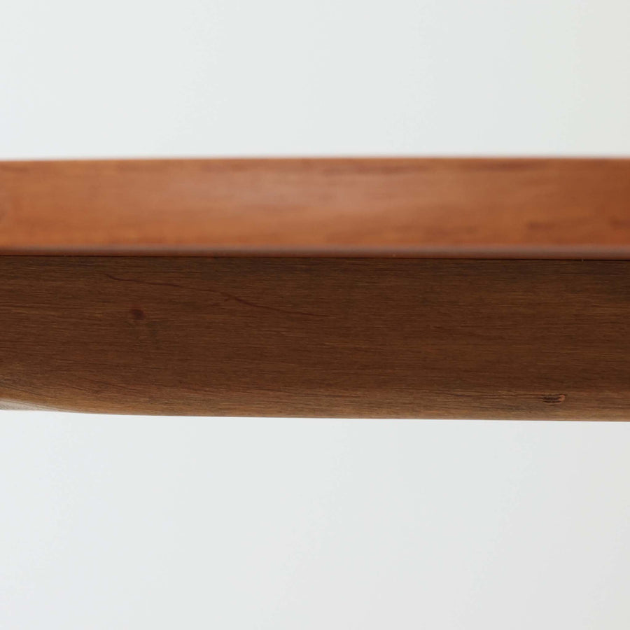 デンマークの巨匠Hans J. Wegner（ハンス・J・ウェグナー）がAndreas Tuck社のためにデザインした「AT8」円形センターテーブルです。チーク材による滑らかな天板と、3本脚の軽やかな構造が特徴で、美しくテーパーのついた脚部が全体に上品な印象を与えます。脚は木製のねじ込み構造になっており、工具を使わずに着脱が可能です。こうしたディテールにもビンテージ期ならではの職人技が感じられます。脚部までチーク材が使用された希少なタイプで、素材の統一感と温かみのある質感が際立ちます。ウェグナーらしいシンプルで機能的な造形と、経年により深みを増したチークの風合いが融合し、リビング空間に上質な北欧のぬくもりを添える一台です。