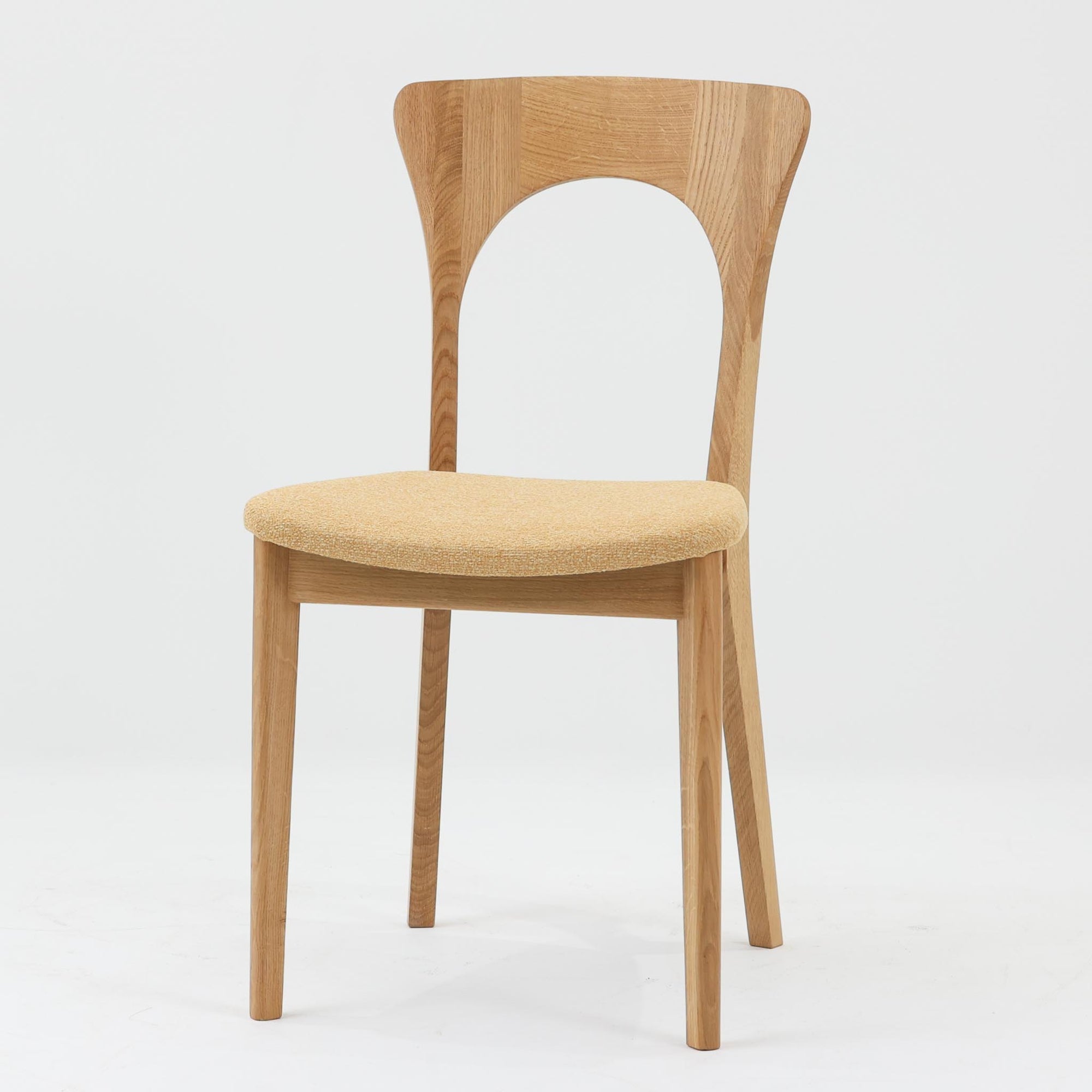 Niels Koefoedが1957年にデザインし、現在はCaso Furnitureより復刻製作されているモデル「Peter」のダイニングチェアです。オーク材の美しい木目を活かしたフレームと、背もたれに大きく設けられたアーチ状の開口部が印象的で、軽やかさと構造的な強度を両立したデザインが特徴です。身体をやさしく受け止める背のラインと、適度なクッション性を備えた座面により、日常使いにおいても快適な座り心地を実現しています。素材の質感を活かしたシンプルな佇まいは、ダイニング空間に自然と馴染み、北欧ミッドセンチュリー期のデザインらしい温かみと洗練を感じさせる一脚です。
