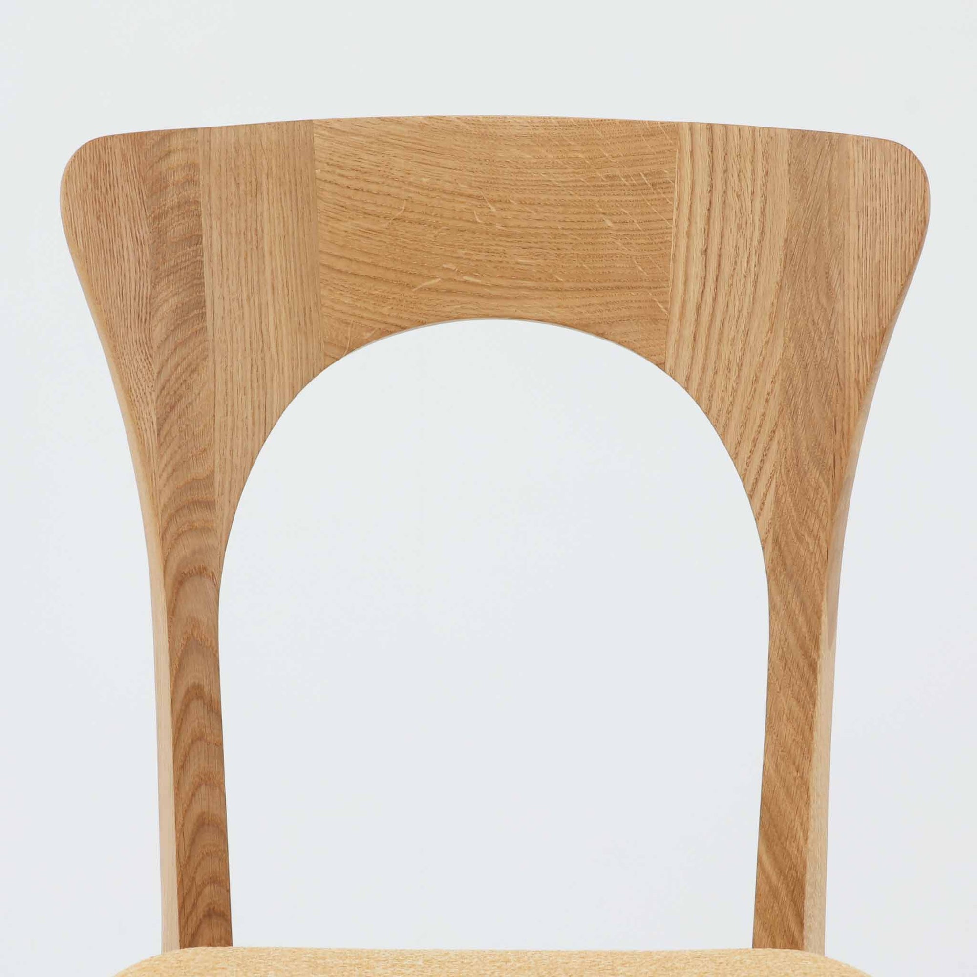 Niels Koefoedが1957年にデザインし、現在はCaso Furnitureより復刻製作されているモデル「Peter」のダイニングチェアです。オーク材の美しい木目を活かしたフレームと、背もたれに大きく設けられたアーチ状の開口部が印象的で、軽やかさと構造的な強度を両立したデザインが特徴です。身体をやさしく受け止める背のラインと、適度なクッション性を備えた座面により、日常使いにおいても快適な座り心地を実現しています。素材の質感を活かしたシンプルな佇まいは、ダイニング空間に自然と馴染み、北欧ミッドセンチュリー期のデザインらしい温かみと洗練を感じさせる一脚です。