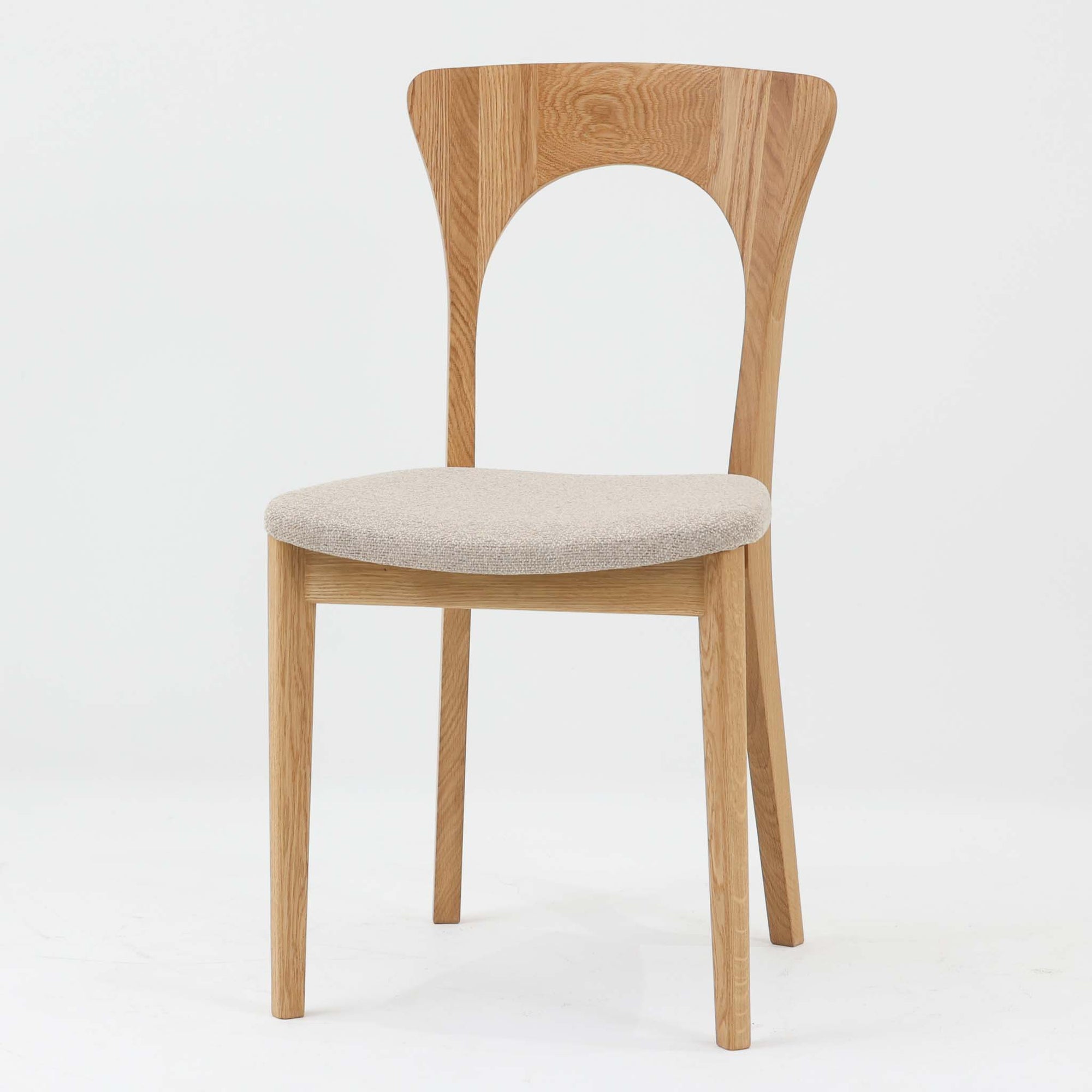 Niels Koefoedが1957年にデザインし、現在はCaso Furnitureより復刻製作されているモデル「Peter」のダイニングチェアです。オーク材の美しい木目を活かしたフレームと、背もたれに大きく設けられたアーチ状の開口部が印象的で、軽やかさと構造的な強度を両立したデザインが特徴です。身体をやさしく受け止める背のラインと、適度なクッション性を備えた座面により、日常使いにおいても快適な座り心地を実現しています。素材の質感を活かしたシンプルな佇まいは、ダイニング空間に自然と馴染み、北欧ミッドセンチュリー期のデザインらしい温かみと洗練を感じさせる一脚です。