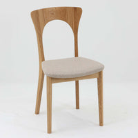 Niels Koefoedが1957年にデザインし、現在はCaso Furnitureより復刻製作されているモデル「Peter」のダイニングチェアです。オーク材の美しい木目を活かしたフレームと、背もたれに大きく設けられたアーチ状の開口部が印象的で、軽やかさと構造的な強度を両立したデザインが特徴です。身体をやさしく受け止める背のラインと、適度なクッション性を備えた座面により、日常使いにおいても快適な座り心地を実現しています。素材の質感を活かしたシンプルな佇まいは、ダイニング空間に自然と馴染み、北欧ミッドセンチュリー期のデザインらしい温かみと洗練を感じさせる一脚です。