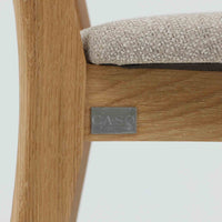 Niels Koefoedが1957年にデザインし、現在はCaso Furnitureより復刻製作されているモデル「Peter」のダイニングチェアです。オーク材の美しい木目を活かしたフレームと、背もたれに大きく設けられたアーチ状の開口部が印象的で、軽やかさと構造的な強度を両立したデザインが特徴です。身体をやさしく受け止める背のラインと、適度なクッション性を備えた座面により、日常使いにおいても快適な座り心地を実現しています。素材の質感を活かしたシンプルな佇まいは、ダイニング空間に自然と馴染み、北欧ミッドセンチュリー期のデザインらしい温かみと洗練を感じさせる一脚です。