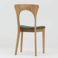 Niels Koefoedが1957年にデザインし、現在はCaso Furnitureより復刻製作されているモデル「Peter」のダイニングチェアです。オーク材の美しい木目を活かしたフレームと、背もたれに大きく設けられたアーチ状の開口部が印象的で、軽やかさと構造的な強度を両立したデザインが特徴です。身体をやさしく受け止める背のラインと、適度なクッション性を備えた座面により、日常使いにおいても快適な座り心地を実現しています。素材の質感を活かしたシンプルな佇まいは、ダイニング空間に自然と馴染み、北欧ミッドセンチュリー期のデザインらしい温かみと洗練を感じさせる一脚です。