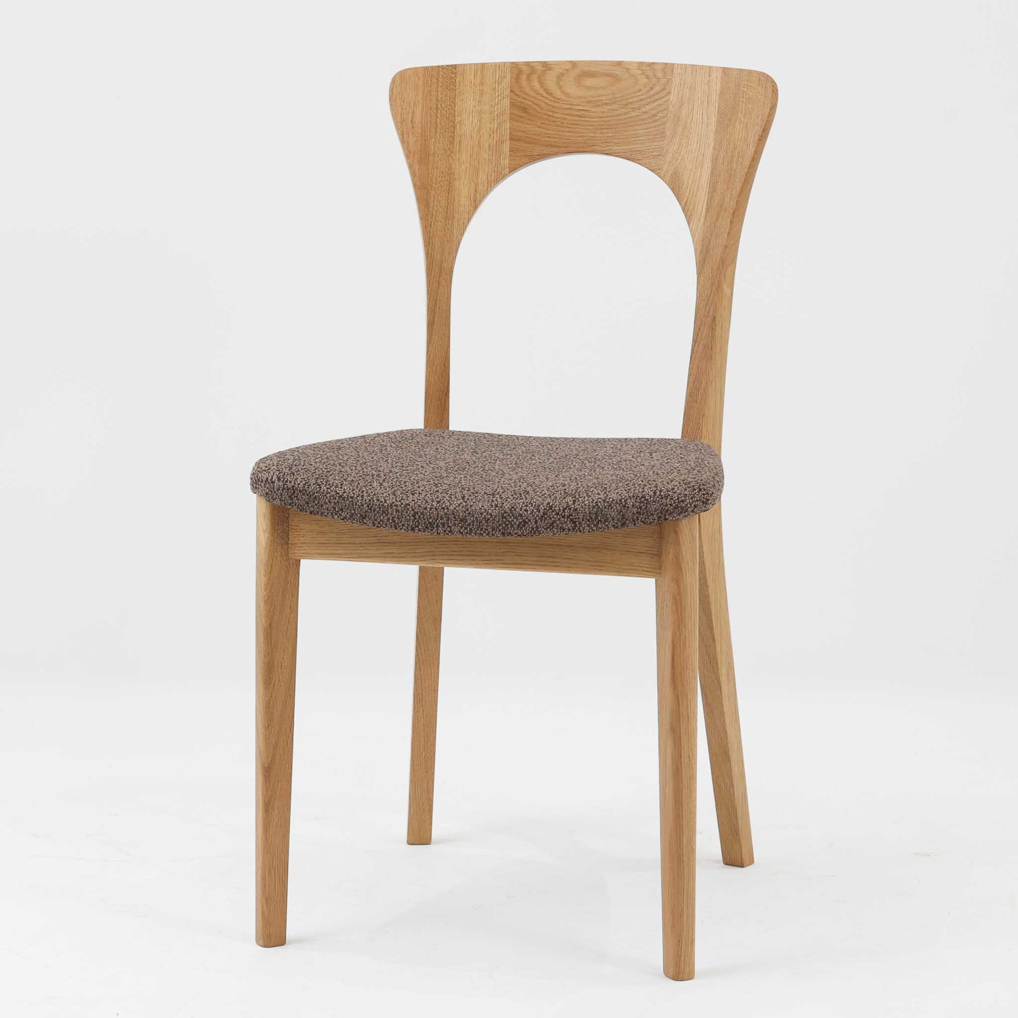 Niels Koefoedが1957年にデザインし、現在はCaso Furnitureより復刻製作されているモデル「Peter」のダイニングチェアです。オーク材の美しい木目を活かしたフレームと、背もたれに大きく設けられたアーチ状の開口部が印象的で、軽やかさと構造的な強度を両立したデザインが特徴です。身体をやさしく受け止める背のラインと、適度なクッション性を備えた座面により、日常使いにおいても快適な座り心地を実現しています。素材の質感を活かしたシンプルな佇まいは、ダイニング空間に自然と馴染み、北欧ミッドセンチュリー期のデザインらしい温かみと洗練を感じさせる一脚です。