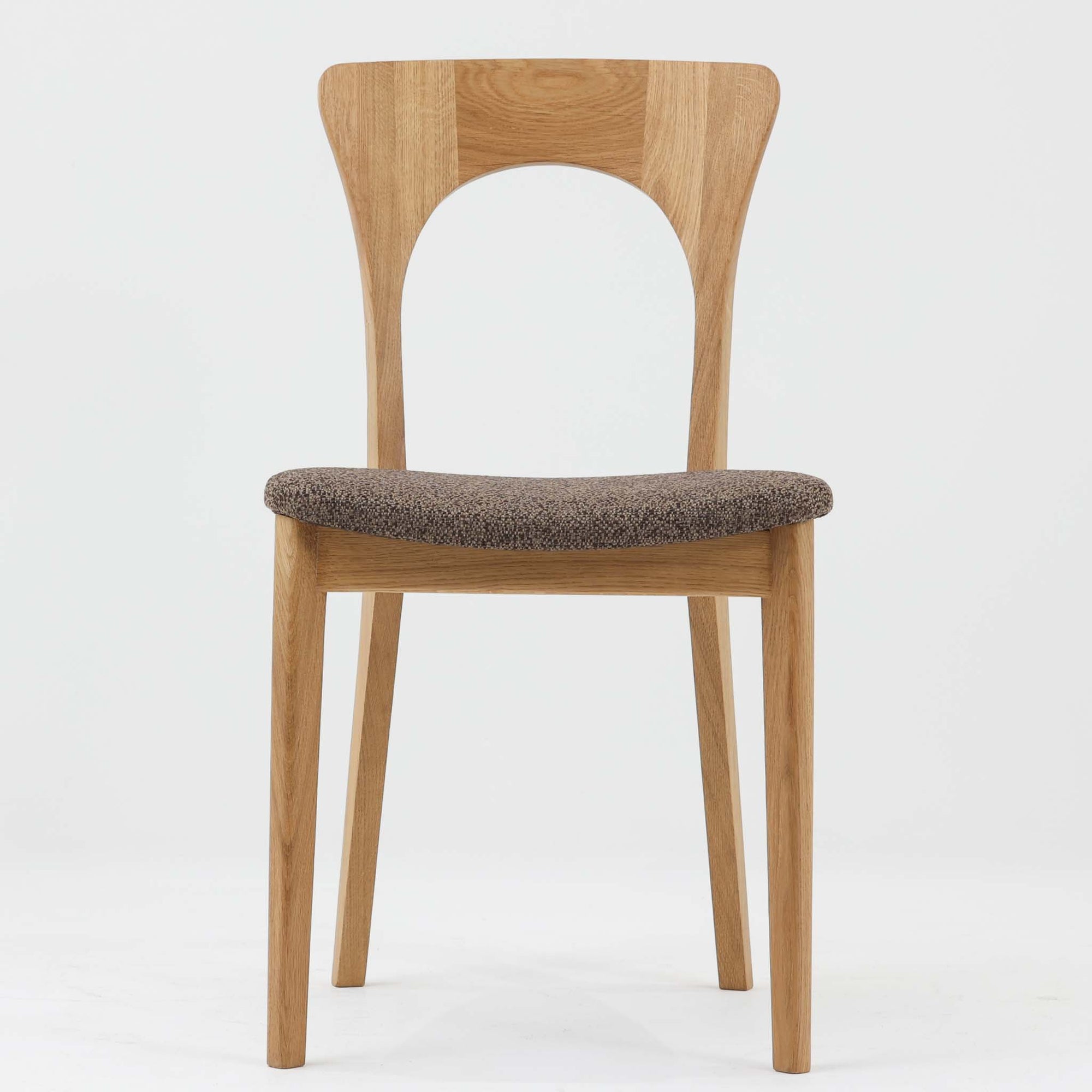 Niels Koefoedが1957年にデザインし、現在はCaso Furnitureより復刻製作されているモデル「Peter」のダイニングチェアです。オーク材の美しい木目を活かしたフレームと、背もたれに大きく設けられたアーチ状の開口部が印象的で、軽やかさと構造的な強度を両立したデザインが特徴です。身体をやさしく受け止める背のラインと、適度なクッション性を備えた座面により、日常使いにおいても快適な座り心地を実現しています。素材の質感を活かしたシンプルな佇まいは、ダイニング空間に自然と馴染み、北欧ミッドセンチュリー期のデザインらしい温かみと洗練を感じさせる一脚です。