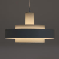 Jo HammerborgがFog & Morupのためにデザインした「Equator」は、直径40cmの存在感あるスチール製ペンダントライトで、赤・黄色・青など多彩なカラーバリエーションが展開されていたモデルとして知られますが、本品は空間に優しく溶け込む上品なホワイトカラーが採用されています。スチール特有の程よい重量感と重厚な佇まいがあり、実際に吊るすとホワイトの柔らかな印象の中にしっかりとした質感が感じられるのも魅力です。同心円状に重なるシェードが光を柔らかく分散させ、眩しさを抑えつつ立体的な陰影を生み出す構造が特徴で、ダイニングやリビングの主照明として落ち着きのあるモダンなアクセントを添えます。ミニマルな造形の中に職人技が凝縮されており、経年で深まった塗装の質感がビンテージならではの魅力を一層引き立てています。