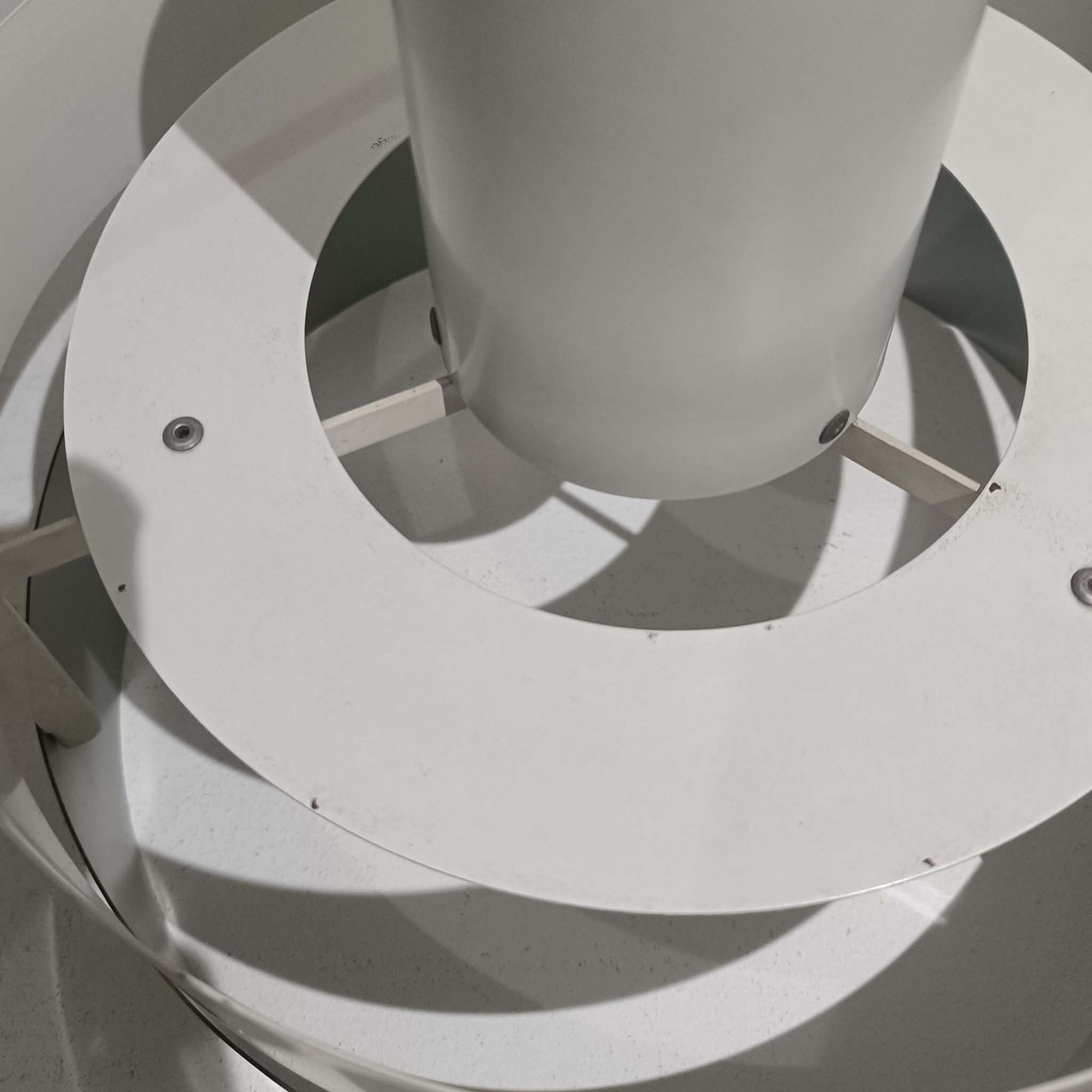 Jo HammerborgがFog &amp; Morupのためにデザインした「Equator」は、直径40cmの存在感あるスチール製ペンダントライトで、赤・黄色・青など多彩なカラーバリエーションが展開されていたモデルとして知られますが、本品は空間に優しく溶け込む上品なホワイトカラーが採用されています。スチール特有の程よい重量感と重厚な佇まいがあり、実際に吊るすとホワイトの柔らかな印象の中にしっかりとした質感が感じられるのも魅力です。同心円状に重なるシェードが光を柔らかく分散させ、眩しさを抑えつつ立体的な陰影を生み出す構造が特徴で、ダイニングやリビングの主照明として落ち着きのあるモダンなアクセントを添えます。ミニマルな造形の中に職人技が凝縮されており、経年で深まった塗装の質感がビンテージならではの魅力を一層引き立てています。