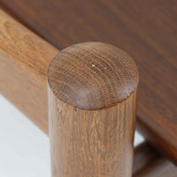 Hans J. Wegnerがデザインし、Getamaが製作したGE530オットマンです。ダークオーク材の力強い木目を活かした角の取れたフレームと、丸脚を組み合わせた端正な構造が特徴で、裏面には刻印も確認できます。程よい厚みのクッションは張り替え済みで、軽やかな生地が木部の深みのある色合いを引き立てます。同シリーズのラウンジチェアと合わせてはもちろん、単体でスツールや補助椅子としても活躍する、北欧ビンテージならではの質実剛健な一品です。