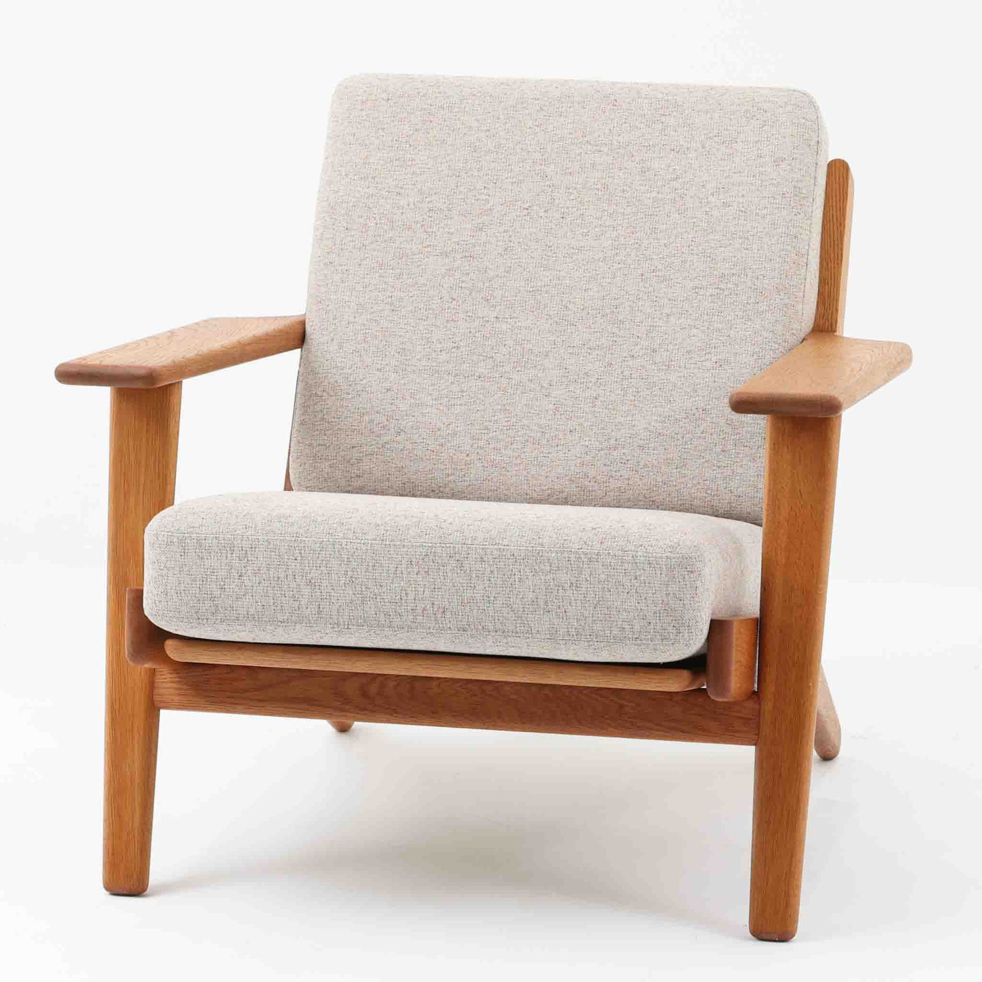 Hans J. Wegnerがデザインし、Getama社によって製作されたGE290は、構造の美しさと快適な座り心地を兼ね備えた北欧ビンテージを代表するシングルソファです。厚みのあるクッションと緩やかに傾斜した背もたれが身体を包み込み、自然と深いリラックス姿勢へと導きます。クッション内部にはビンテージ品ならではのスプリングが内包されており、しっかりとした弾力と安定感のある座り心地を生み出しています。オーク材のフレームは力強さと温かみを併せ持ち、アームから脚部にかけての造形にはウェグナーらしい彫刻的な魅力が感じられます。張地の落ち着いた色合いと、経年により深みを増した木部の表情が調和し、リビングや書斎で長く寄り添う一脚です。