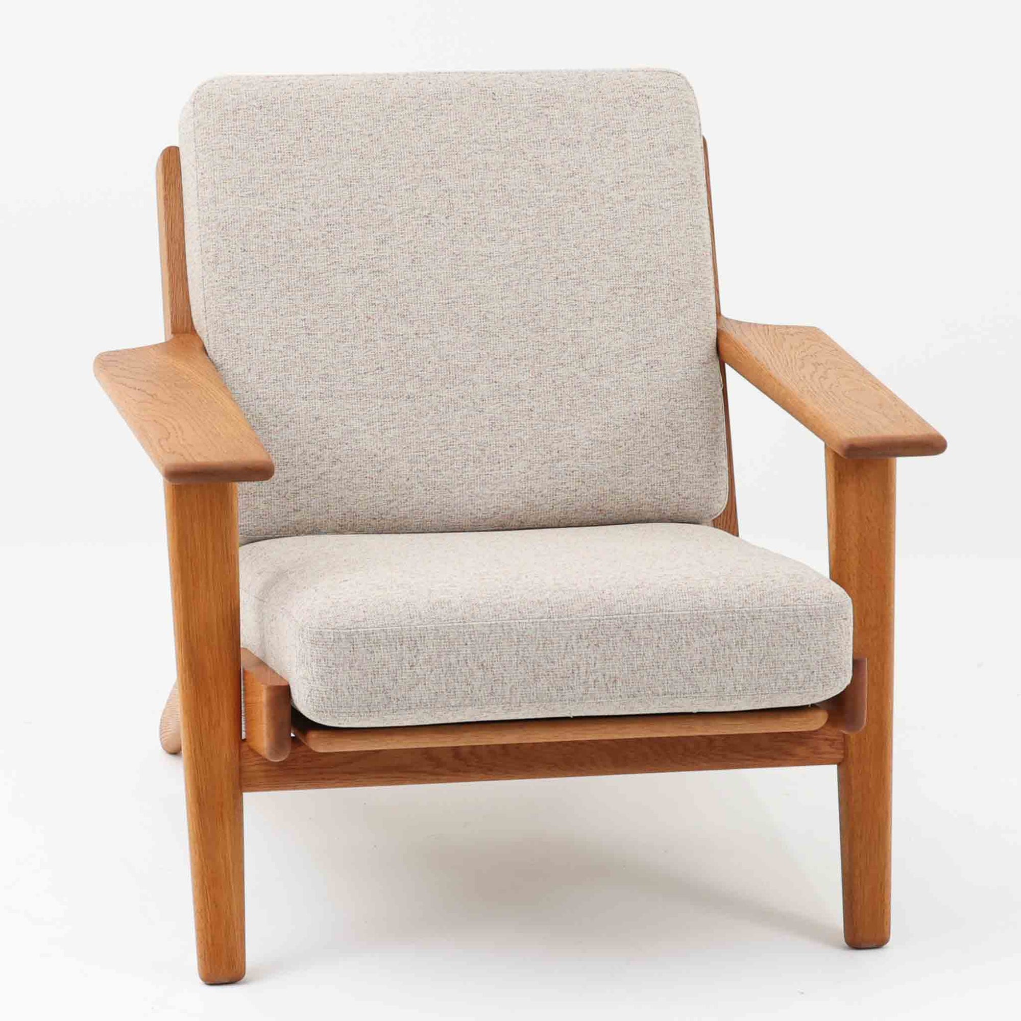 Hans J. Wegnerがデザインし、Getama社によって製作されたGE290は、構造の美しさと快適な座り心地を兼ね備えた北欧ビンテージを代表するシングルソファです。厚みのあるクッションと緩やかに傾斜した背もたれが身体を包み込み、自然と深いリラックス姿勢へと導きます。クッション内部にはビンテージ品ならではのスプリングが内包されており、しっかりとした弾力と安定感のある座り心地を生み出しています。オーク材のフレームは力強さと温かみを併せ持ち、アームから脚部にかけての造形にはウェグナーらしい彫刻的な魅力が感じられます。張地の落ち着いた色合いと、経年により深みを増した木部の表情が調和し、リビングや書斎で長く寄り添う一脚です。