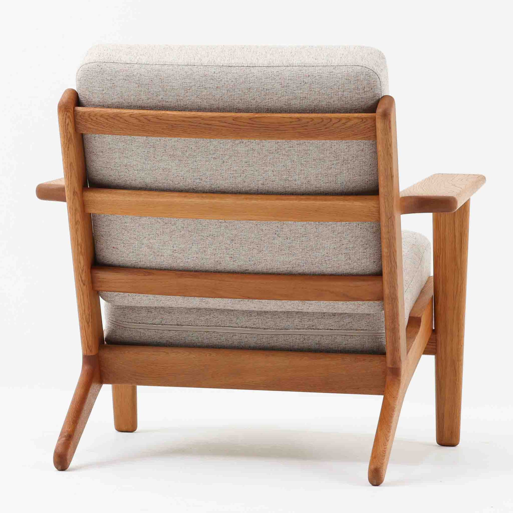 Hans J. Wegnerがデザインし、Getama社によって製作されたGE290は、構造の美しさと快適な座り心地を兼ね備えた北欧ビンテージを代表するシングルソファです。厚みのあるクッションと緩やかに傾斜した背もたれが身体を包み込み、自然と深いリラックス姿勢へと導きます。クッション内部にはビンテージ品ならではのスプリングが内包されており、しっかりとした弾力と安定感のある座り心地を生み出しています。オーク材のフレームは力強さと温かみを併せ持ち、アームから脚部にかけての造形にはウェグナーらしい彫刻的な魅力が感じられます。張地の落ち着いた色合いと、経年により深みを増した木部の表情が調和し、リビングや書斎で長く寄り添う一脚です。