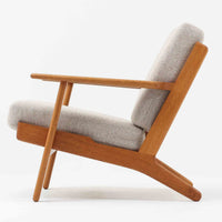 Hans J. Wegnerがデザインし、Getama社によって製作されたGE290は、構造の美しさと快適な座り心地を兼ね備えた北欧ビンテージを代表するシングルソファです。厚みのあるクッションと緩やかに傾斜した背もたれが身体を包み込み、自然と深いリラックス姿勢へと導きます。クッション内部にはビンテージ品ならではのスプリングが内包されており、しっかりとした弾力と安定感のある座り心地を生み出しています。オーク材のフレームは力強さと温かみを併せ持ち、アームから脚部にかけての造形にはウェグナーらしい彫刻的な魅力が感じられます。張地の落ち着いた色合いと、経年により深みを増した木部の表情が調和し、リビングや書斎で長く寄り添う一脚です。