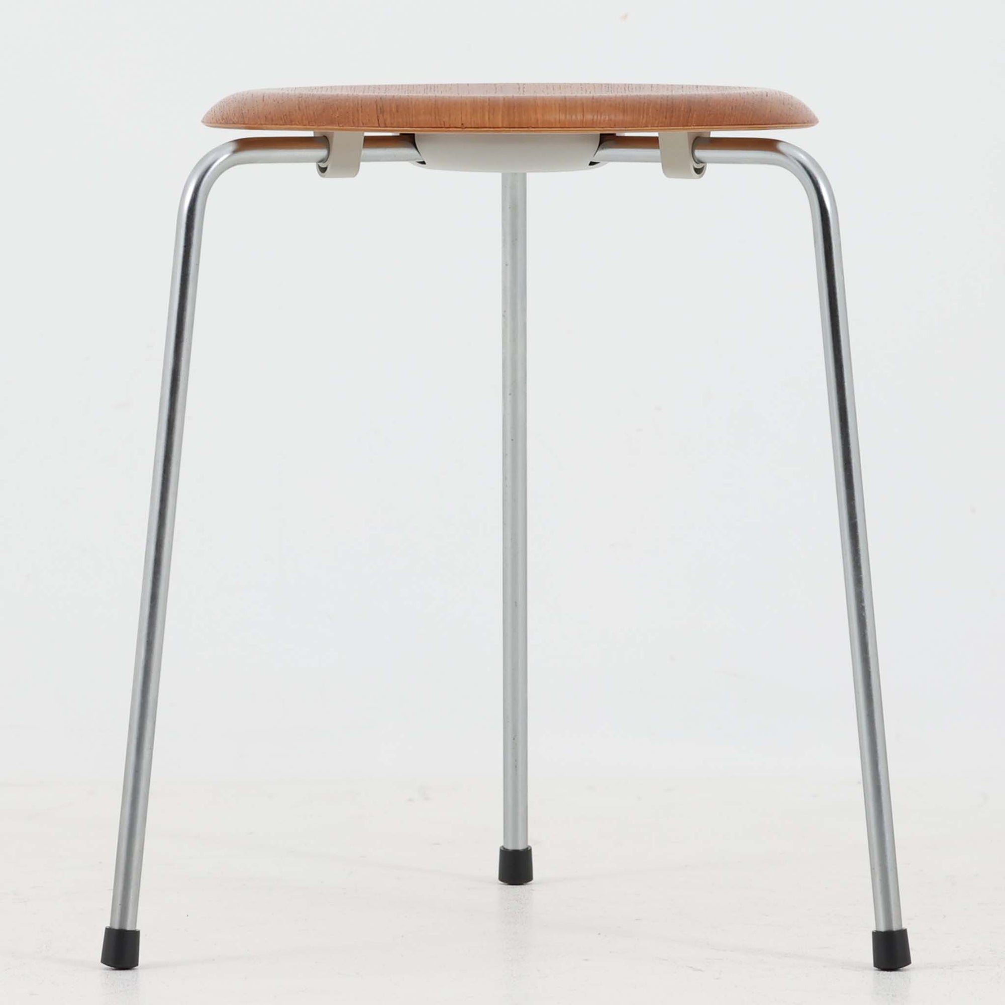 Arne Jacobsen（アルネ・ヤコブセン）がFritz Hansen（フリッツ・ハンセン）のために手掛けた有名なドットスツールは、チーク材の座面とスチールレッグを組み合わせた軽快な佇まいが魅力の北欧ビンテージ家具で、中でも希少なチークモデルとなるこちらは滑らかに成形された丸い座面が身体に心地よくフィットし、わずかに外側へ開いた3本脚が安定感を確保しつつ空間に軽やかな印象を添え、ミニマルな構造に宿る職人技と経年で深まった木肌と金属のコントラストが美しく、ダイニングのサブチェアや玄関、デスク横のサイドスツールとしても取り入れやすい一脚です。