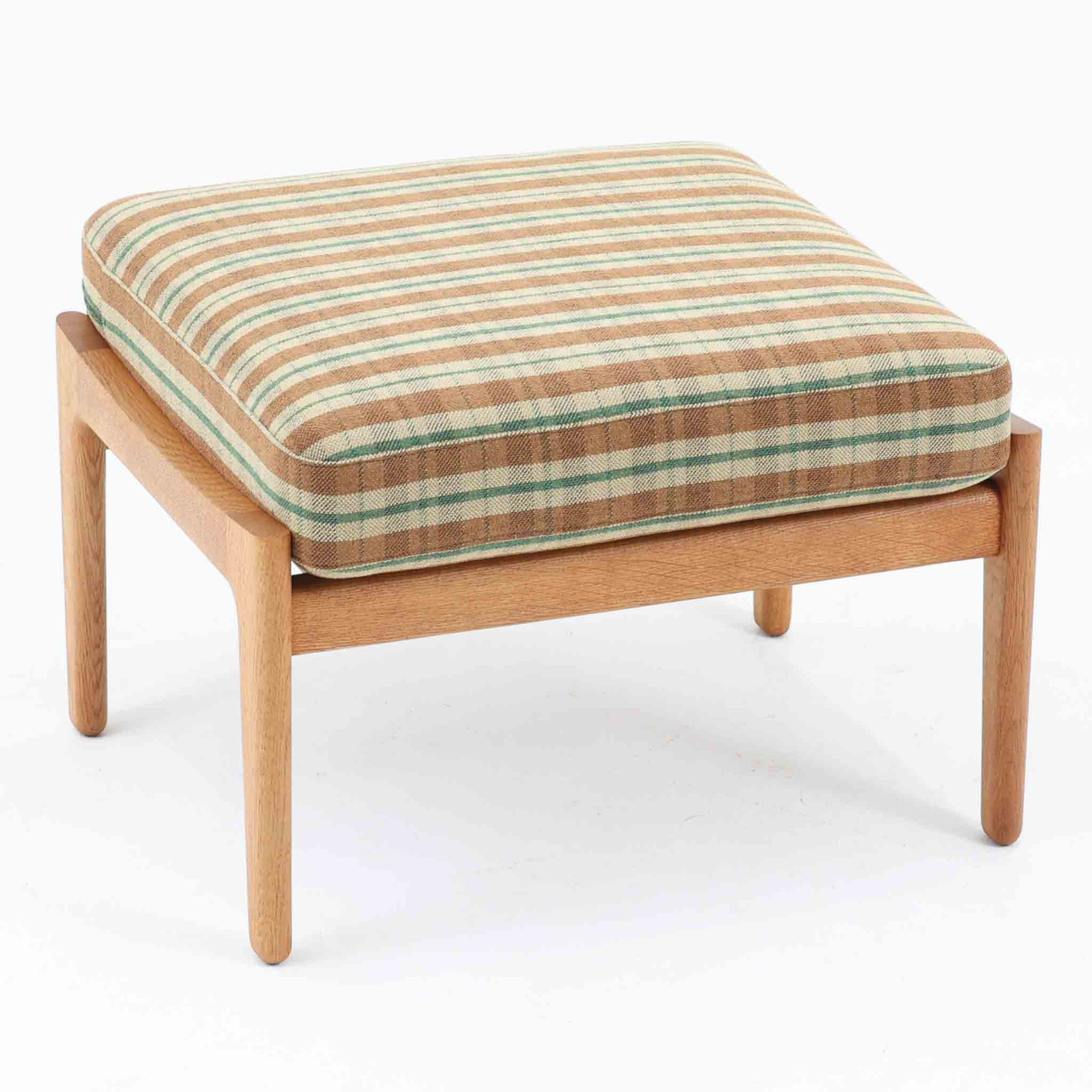 Hans J. Wegnerがデザインし、Getamaが製作したGE290オットマンです。オーク材の美しい木目を活かした無垢フレームは、丸みを帯びた脚部と貫構造により安定感と軽やかさを兼ね備えています。クッションは張り替え済みで、落ち着いたストライプ柄が木部の温かな色合いを引き立てます。同シリーズのラウンジチェアと組み合わせて快適な寛ぎを演出するのはもちろん、単体でもスツールとして活躍。経年で深みを増した素材感が、北欧ビンテージならではの上質な存在感を放つ一品です。クッション内部にはビンテージ品ならではのスプリングが内包されています。