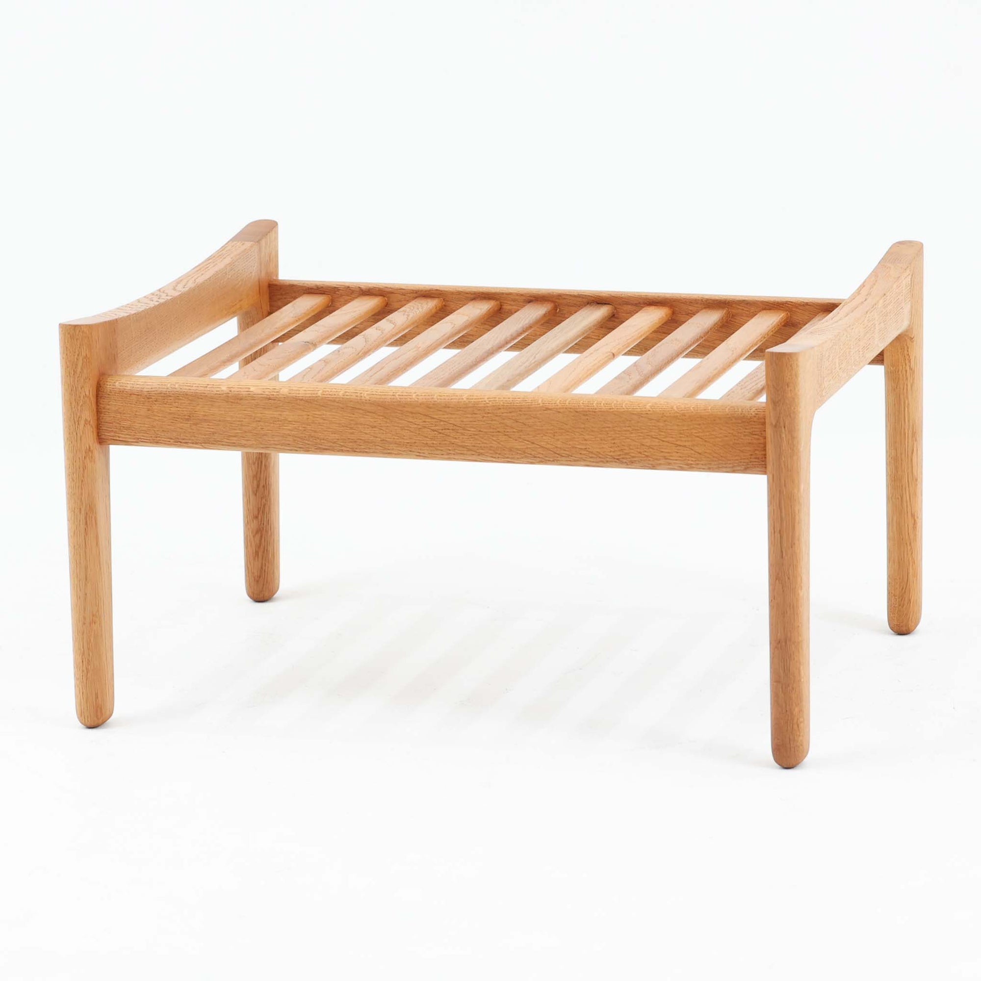 Hans J. Wegnerがデザインし、Getamaが製作したGE290オットマンです。オーク材の美しい木目を活かした無垢フレームは、丸みを帯びた脚部と貫構造により安定感と軽やかさを兼ね備えています。クッションは張り替え済みで、落ち着いたストライプ柄が木部の温かな色合いを引き立てます。同シリーズのラウンジチェアと組み合わせて快適な寛ぎを演出するのはもちろん、単体でもスツールとして活躍。経年で深みを増した素材感が、北欧ビンテージならではの上質な存在感を放つ一品です。クッション内部にはビンテージ品ならではのスプリングが内包されています。