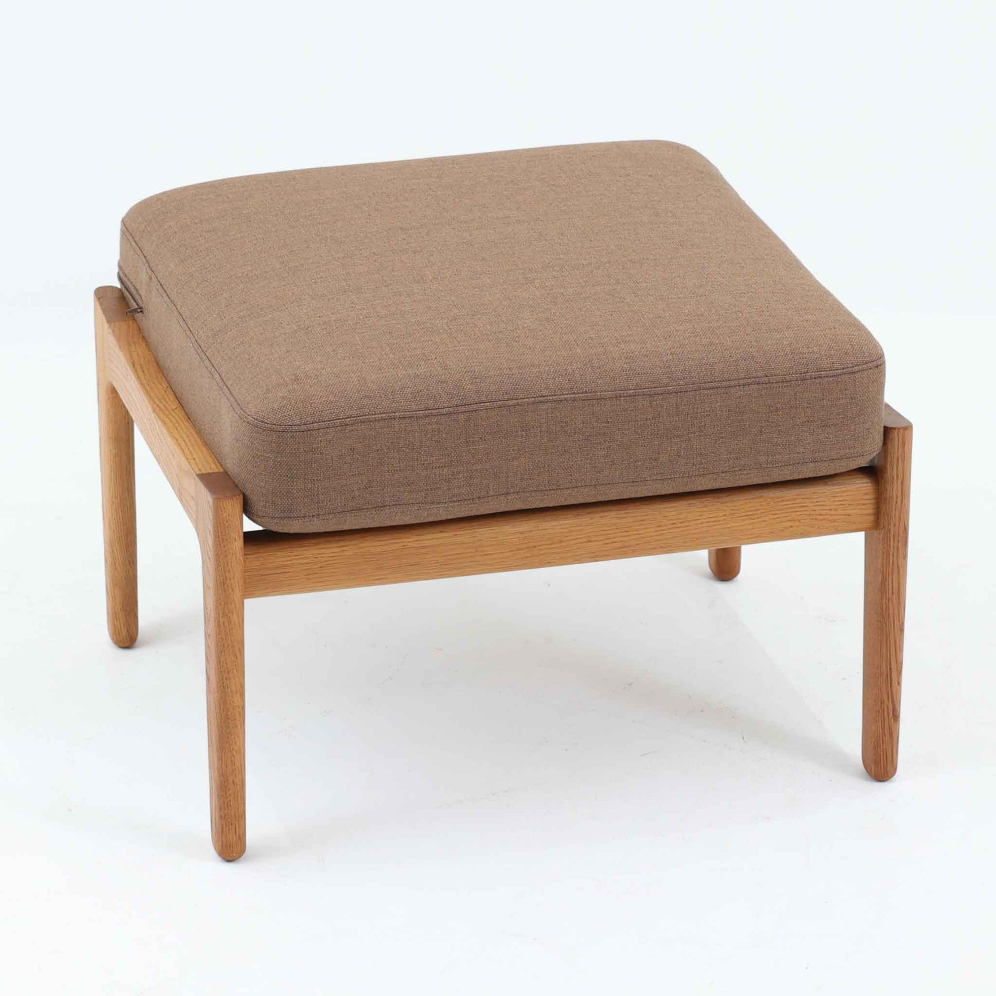 Hans J. Wegnerがデザインし、Getamaが製作したGE290オットマンです。オーク材の美しい木目を活かした無垢フレームは、丸みを帯びた脚部と貫構造により安定感と軽やかさを兼ね備えています。クッションは張り替え済みで、ライトブラウン色の張地が木部の温かな色合いと調和し、落ち着いた印象を与えます。内部にはビンテージ品ならではのスプリングが内包され、弾力ある座り心地も魅力。同シリーズのラウンジチェアと組み合わせてはもちろん、単体でもスツールとして活躍する、経年変化の味わい深い一品です。