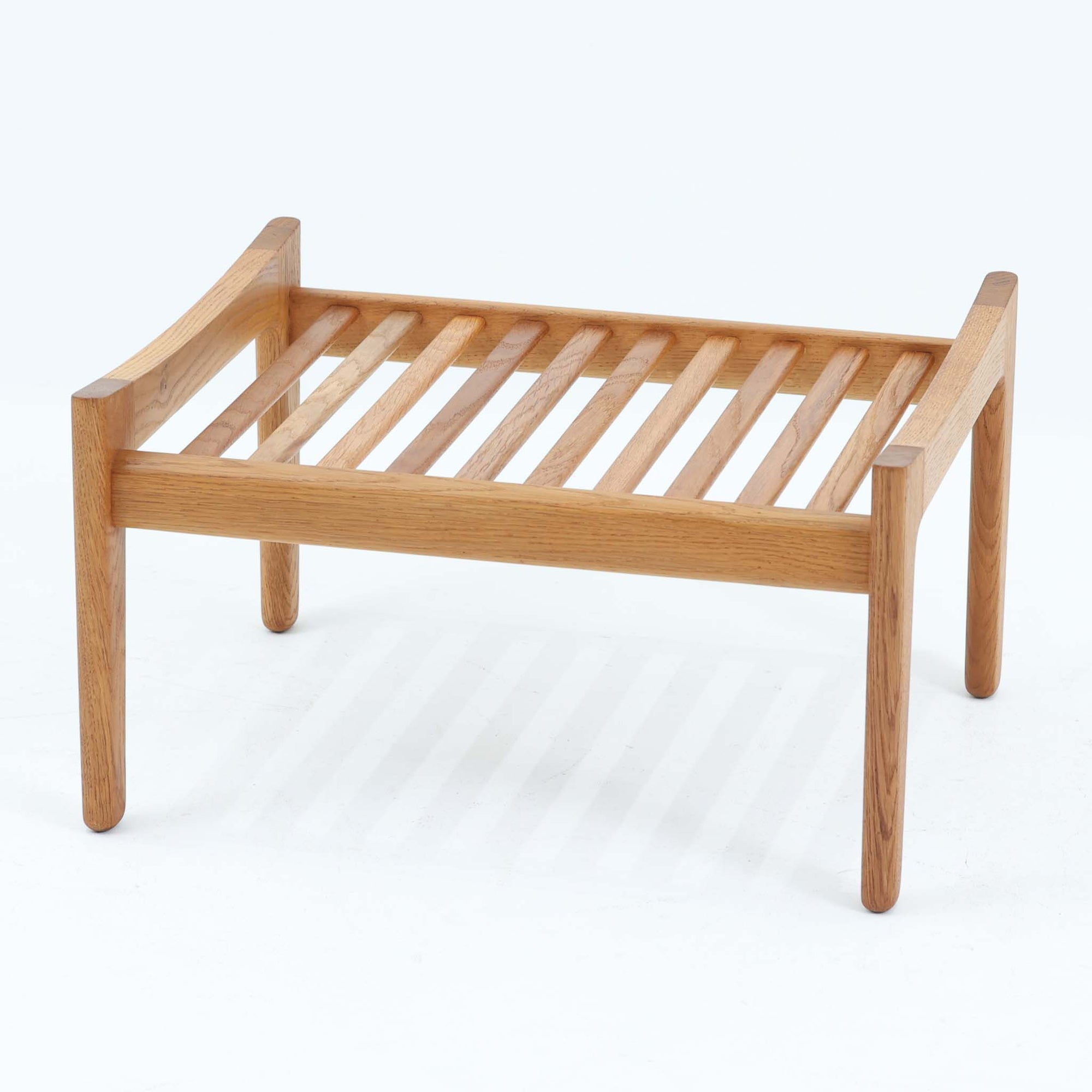 Hans J. Wegnerがデザインし、Getamaが製作したGE290オットマンです。オーク材の美しい木目を活かした無垢フレームは、丸みを帯びた脚部と貫構造により安定感と軽やかさを兼ね備えています。クッションは張り替え済みで、ライトブラウン色の張地が木部の温かな色合いと調和し、落ち着いた印象を与えます。内部にはビンテージ品ならではのスプリングが内包され、弾力ある座り心地も魅力。同シリーズのラウンジチェアと組み合わせてはもちろん、単体でもスツールとして活躍する、経年変化の味わい深い一品です。