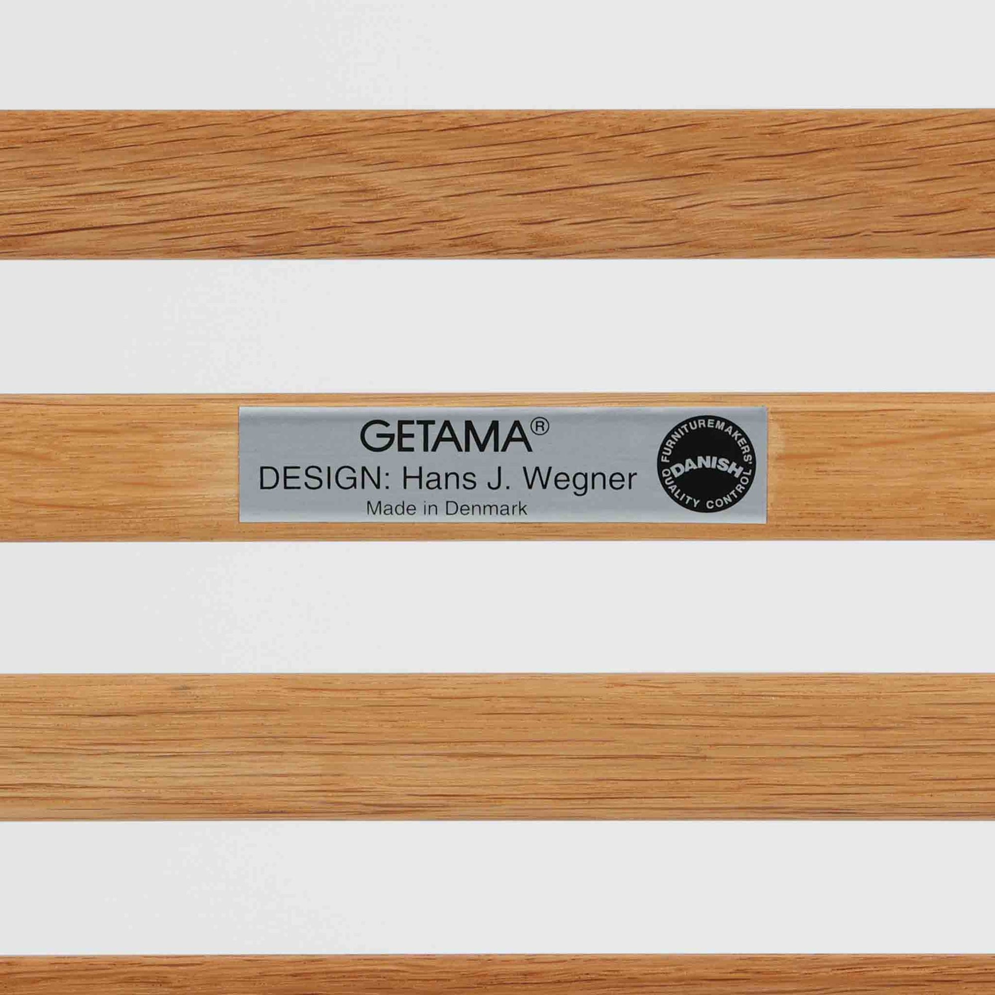 Hans J. Wegnerがデザインし、Getamaが製作したGE290オットマンです。オーク材の美しい木目を活かした無垢フレームは、丸みを帯びた脚部と貫構造により安定感と軽やかさを兼ね備えています。クッションは新たに張り替え済みで、柔らかなサクラ色（ピンク）の張地が、オーク材の温かな質感に優しい彩りを添え、上品で華やかな印象を与えます。内部にはビンテージ品ならではのスプリングが内包され、弾力ある座り心地も魅力。同シリーズのラウンジチェアと組み合わせてはもちろん、単体でもスツールとして活躍する、経年変化の味わい深い一品です。