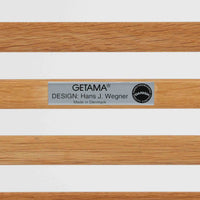 Hans J. Wegnerがデザインし、Getamaが製作したGE290オットマンです。オーク材の美しい木目を活かした無垢フレームは、丸みを帯びた脚部と貫構造により安定感と軽やかさを兼ね備えています。クッションは新たに張り替え済みで、柔らかなサクラ色（ピンク）の張地が、オーク材の温かな質感に優しい彩りを添え、上品で華やかな印象を与えます。内部にはビンテージ品ならではのスプリングが内包され、弾力ある座り心地も魅力。同シリーズのラウンジチェアと組み合わせてはもちろん、単体でもスツールとして活躍する、経年変化の味わい深い一品です。