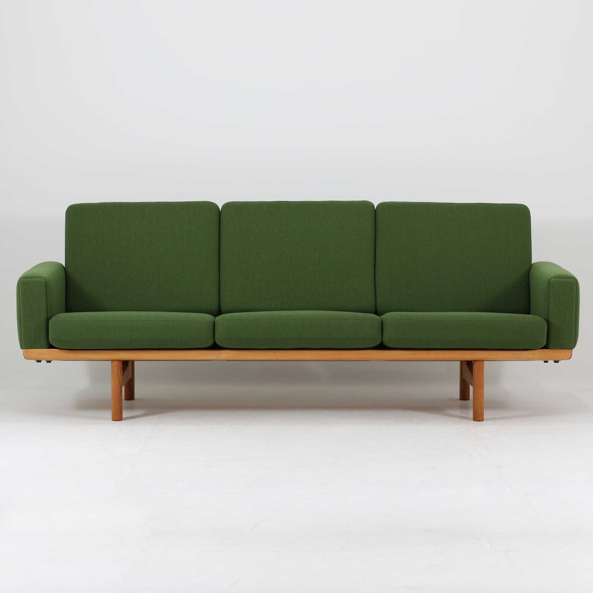 Hans J. Wegnerがデザインし、Getamaより製作されたGE236トリプルソファです。オーク材のフレームと直線を基調とした端正なフォルムが美しく、背面に配された横桟の意匠は後ろ姿まで印象的に演出します。ゆったりとした3人掛けの座面とクッションは快適な座り心地を実現し、リビングの主役として存在感を放ちます。ウェグナーらしい機能美と職人技が息づく設計に加え、経年により深みを増した木肌の風合いが北欧ビンテージならではの魅力を引き立てる希少な一台です。