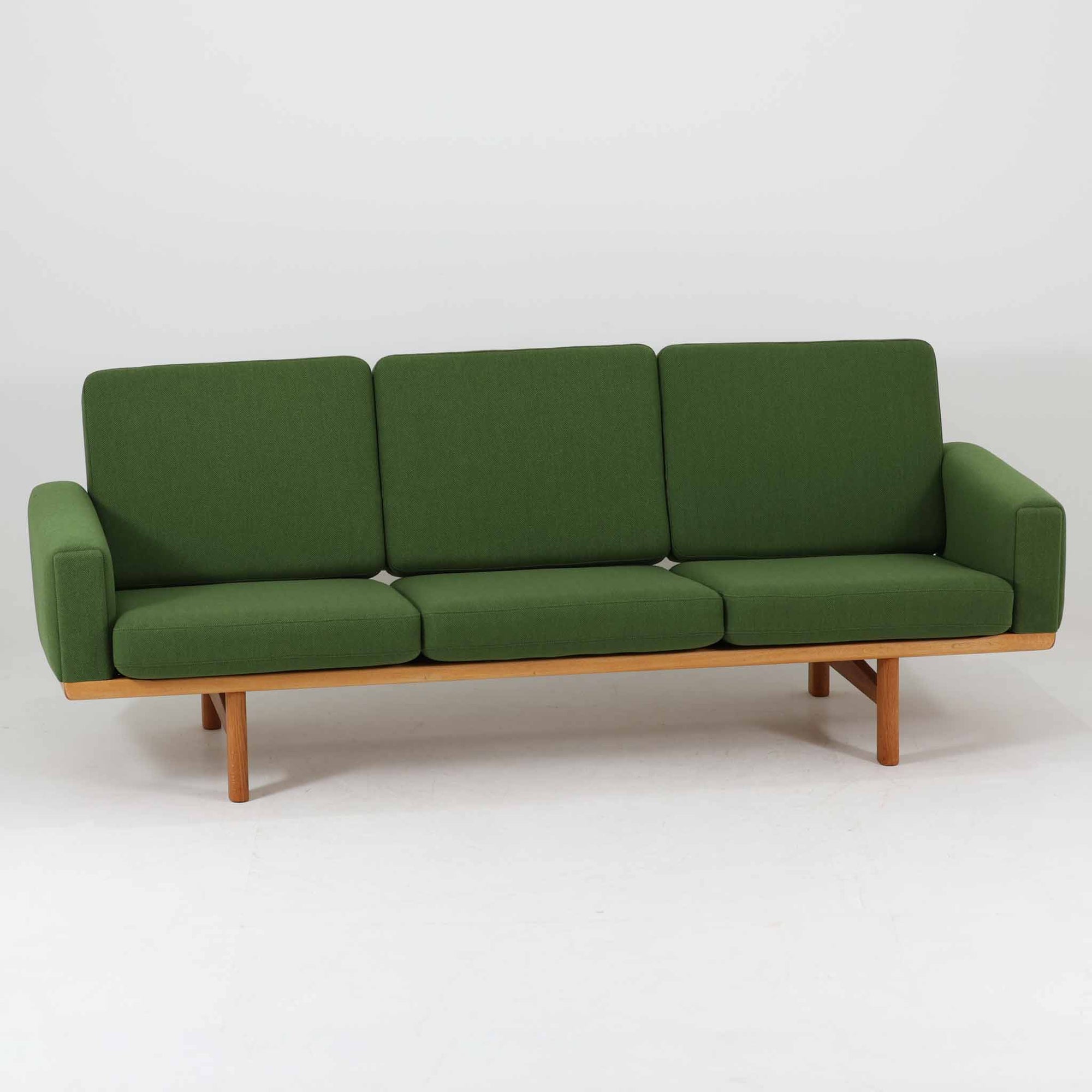 Hans J. Wegnerがデザインし、Getamaより製作されたGE236トリプルソファです。オーク材のフレームと直線を基調とした端正なフォルムが美しく、背面に配された横桟の意匠は後ろ姿まで印象的に演出します。ゆったりとした3人掛けの座面とクッションは快適な座り心地を実現し、リビングの主役として存在感を放ちます。ウェグナーらしい機能美と職人技が息づく設計に加え、経年により深みを増した木肌の風合いが北欧ビンテージならではの魅力を引き立てる希少な一台です。