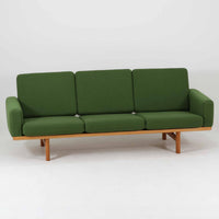 Hans J. Wegnerがデザインし、Getamaより製作されたGE236トリプルソファです。オーク材のフレームと直線を基調とした端正なフォルムが美しく、背面に配された横桟の意匠は後ろ姿まで印象的に演出します。ゆったりとした3人掛けの座面とクッションは快適な座り心地を実現し、リビングの主役として存在感を放ちます。ウェグナーらしい機能美と職人技が息づく設計に加え、経年により深みを増した木肌の風合いが北欧ビンテージならではの魅力を引き立てる希少な一台です。