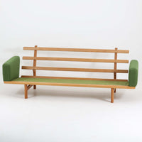 Hans J. Wegnerがデザインし、Getamaより製作されたGE236トリプルソファです。オーク材のフレームと直線を基調とした端正なフォルムが美しく、背面に配された横桟の意匠は後ろ姿まで印象的に演出します。ゆったりとした3人掛けの座面とクッションは快適な座り心地を実現し、リビングの主役として存在感を放ちます。ウェグナーらしい機能美と職人技が息づく設計に加え、経年により深みを増した木肌の風合いが北欧ビンテージならではの魅力を引き立てる希少な一台です。
