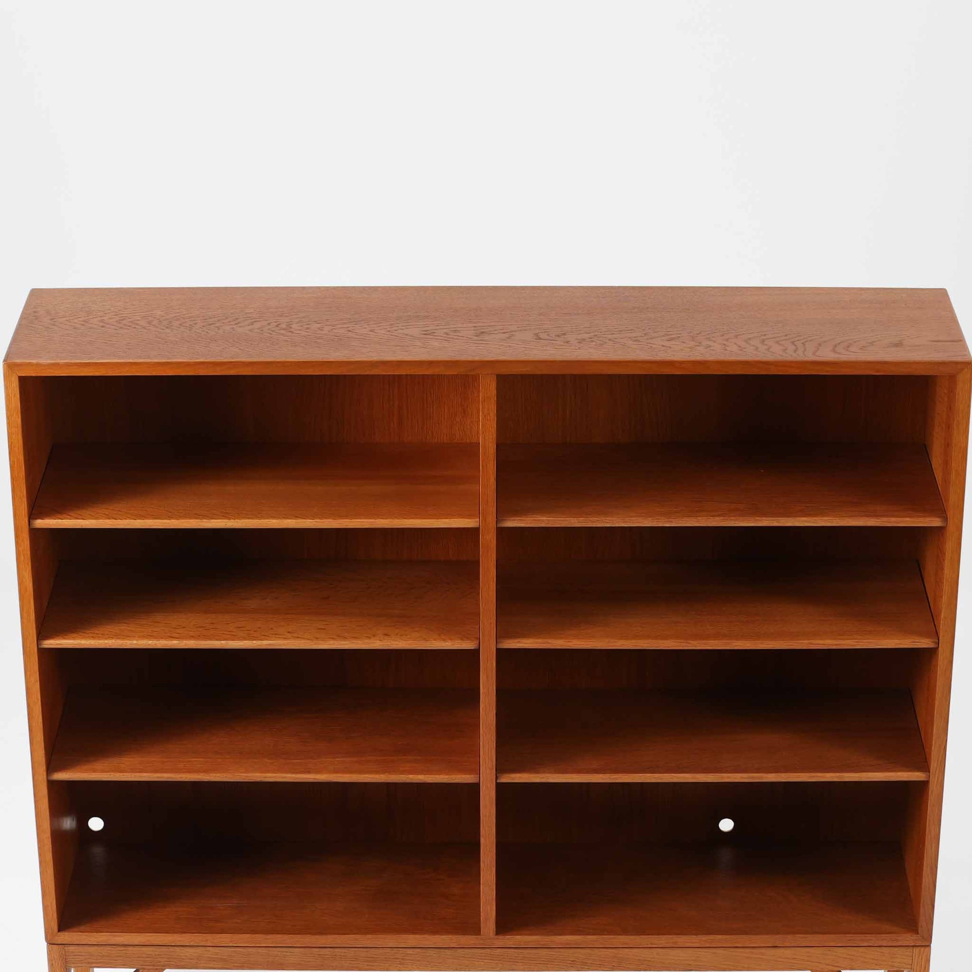 ボーエ・モーエンセンが手がけ、FDB Moblerより製作された北欧ビンテージのブックシェルフです。オーク材の木目を活かした端正で実直な佇まいは、生活に寄り添う家具を追求したデザイン哲学を色濃く感じさせます。左右に分かれた棚構成は収納力に優れ、書籍や器、オブジェまで整然と収められる構造です。特徴的な脚部は後年に付け替えられたものではなく、FDB社で製造されたオリジナル仕様で、取り外すと刻印が確認できます。全体に軽やかさと安定感を与える脚部と、長年の使用によって深みを増した素材感が相まい、空間に静かな存在感とビンテージならではの魅力を添える一台です。