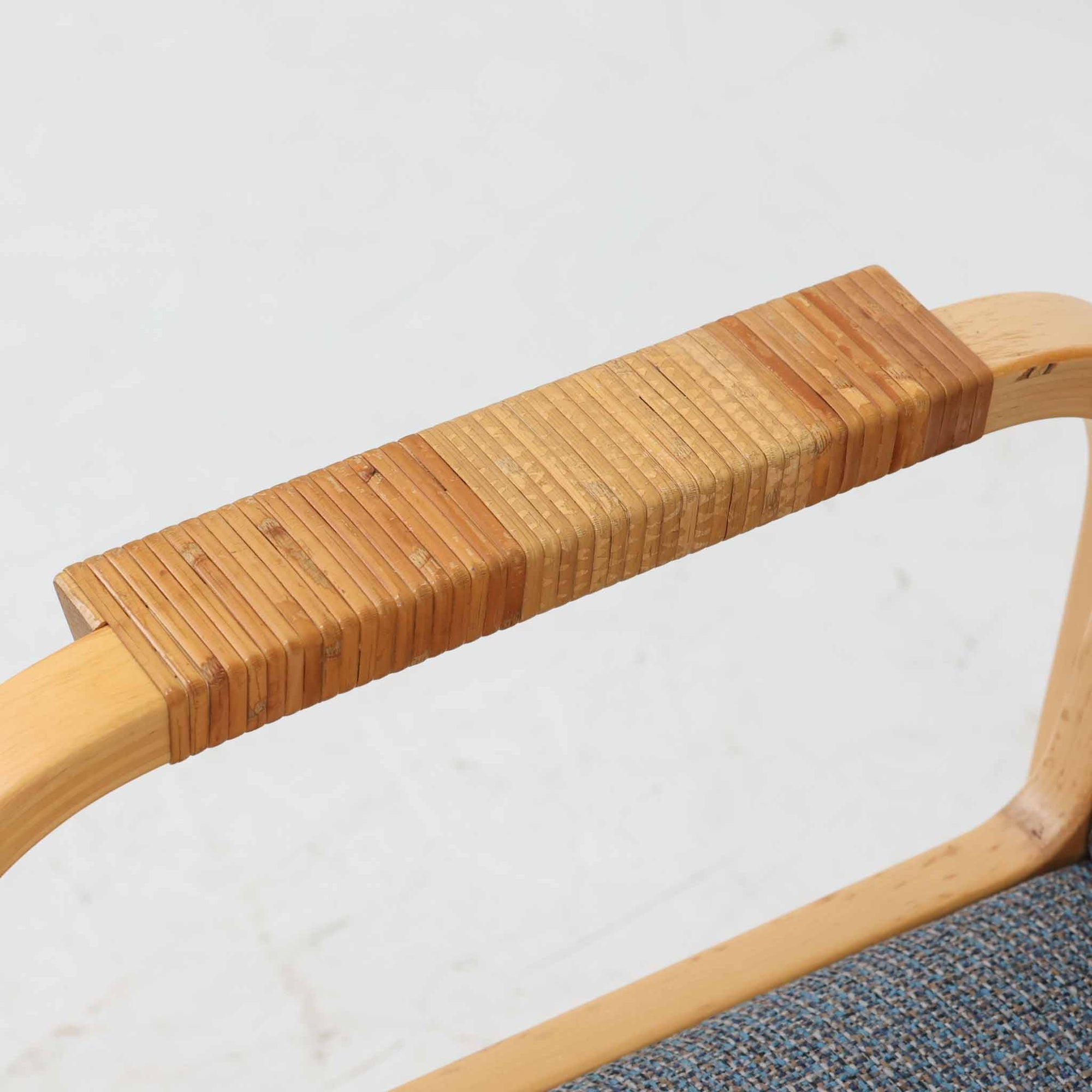 アルヴァ・アアルトが手掛け、アルテックより製作されたモデルE45のアームチェアは、積層バーチ材による滑らかなフレームと、アーム上部に施されたラタン巻きが特徴的な北欧ビンテージの名作です。直線と曲線を巧みに組み合わせた構造は、視覚的な軽やかさと高い強度を両立し、背と座には張りのあるファブリックを用いることで、長時間でも快適な座り心地を実現しています。使い込むほどに木部の色味が深まり、素材の経年変化を楽しめる点も魅力で、ダイニングや書斎、公共空間まで幅広いシーンで活躍する一脚です。