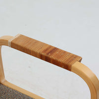 アルヴァ・アアルトが手掛け、アルテックより製作されたモデルE45のアームチェアは、積層バーチ材による滑らかなフレームと、アーム上部に施されたラタン巻きが特徴的な北欧ビンテージの名作です。直線と曲線を巧みに組み合わせた構造は、視覚的な軽やかさと高い強度を両立し、背と座には張りのあるファブリックを用いることで、長時間でも快適な座り心地を実現しています。使い込むほどに木部の色味が深まり、素材の経年変化を楽しめる点も魅力で、ダイニングや書斎、公共空間まで幅広いシーンで活躍する一脚です。