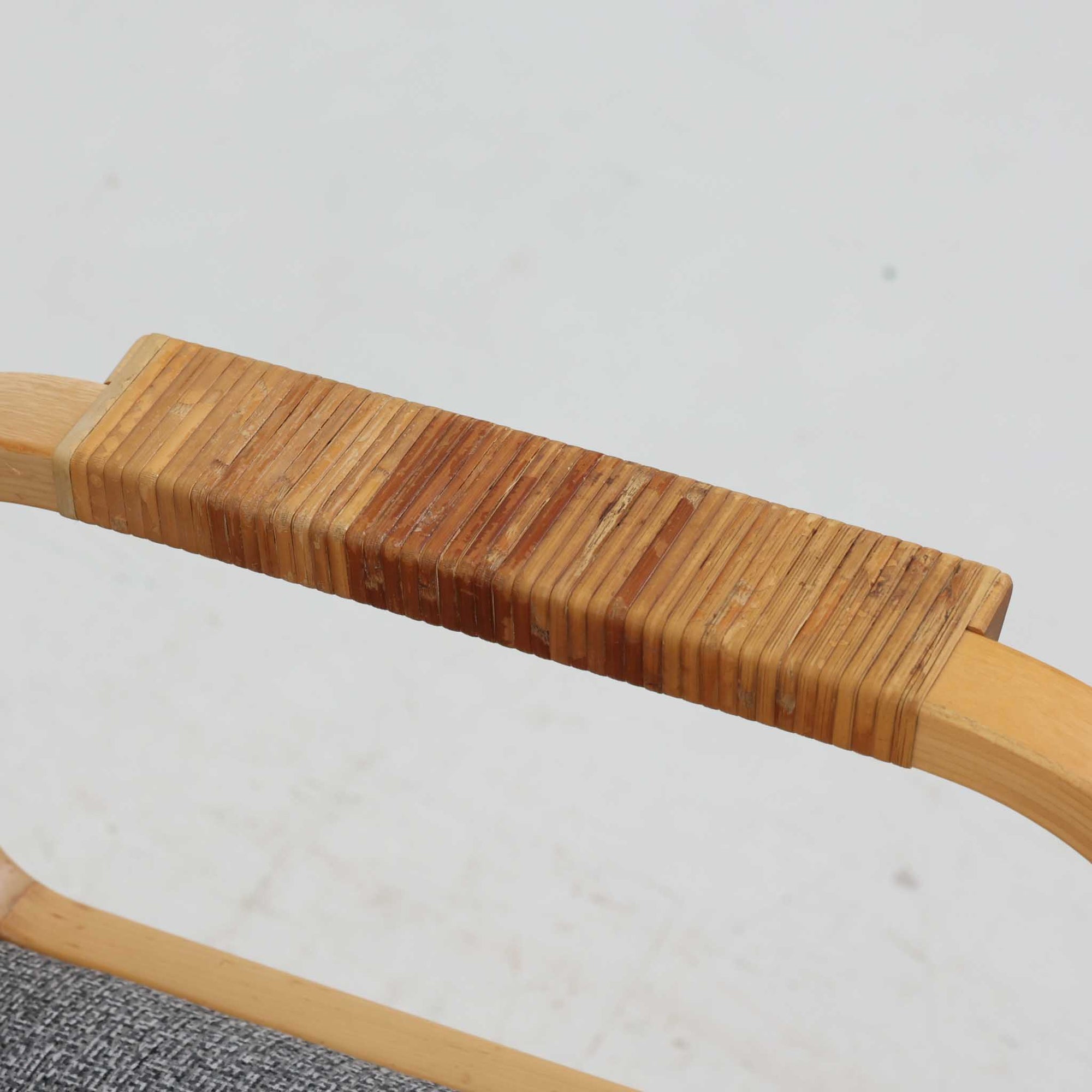 アルヴァ・アアルトが手掛け、アルテックより製作されたモデルE45のアームチェアは、積層バーチ材による滑らかなフレームと、アーム上部に施されたラタン巻きが特徴的な北欧ビンテージの名作です。直線と曲線を巧みに組み合わせた構造は、視覚的な軽やかさと高い強度を両立し、背と座には張りのあるファブリックを用いることで、長時間でも快適な座り心地を実現しています。使い込むほどに木部の色味が深まり、素材の経年変化を楽しめる点も魅力で、ダイニングや書斎、公共空間まで幅広いシーンで活躍する一脚です。