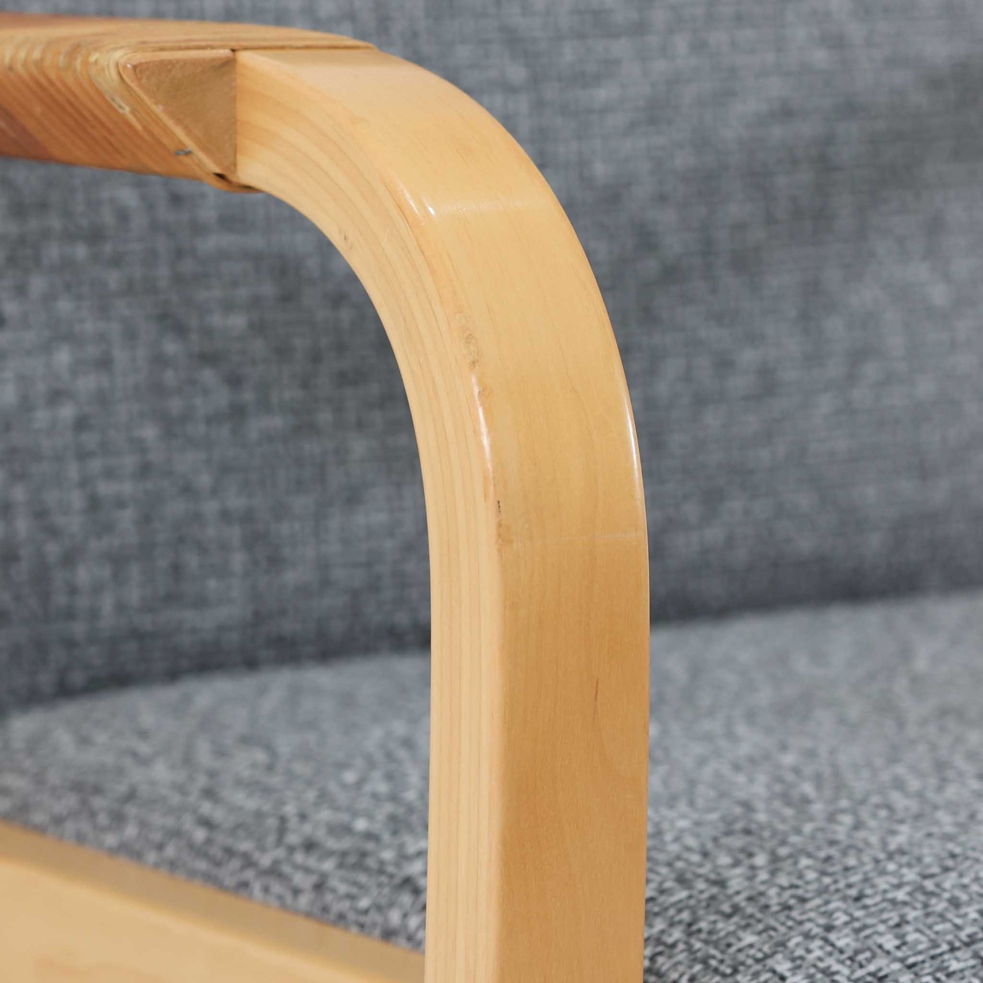 アルヴァ・アアルトが手掛け、アルテックより製作されたモデルE45のアームチェアは、積層バーチ材による滑らかなフレームと、アーム上部に施されたラタン巻きが特徴的な北欧ビンテージの名作です。直線と曲線を巧みに組み合わせた構造は、視覚的な軽やかさと高い強度を両立し、背と座には張りのあるファブリックを用いることで、長時間でも快適な座り心地を実現しています。使い込むほどに木部の色味が深まり、素材の経年変化を楽しめる点も魅力で、ダイニングや書斎、公共空間まで幅広いシーンで活躍する一脚です。