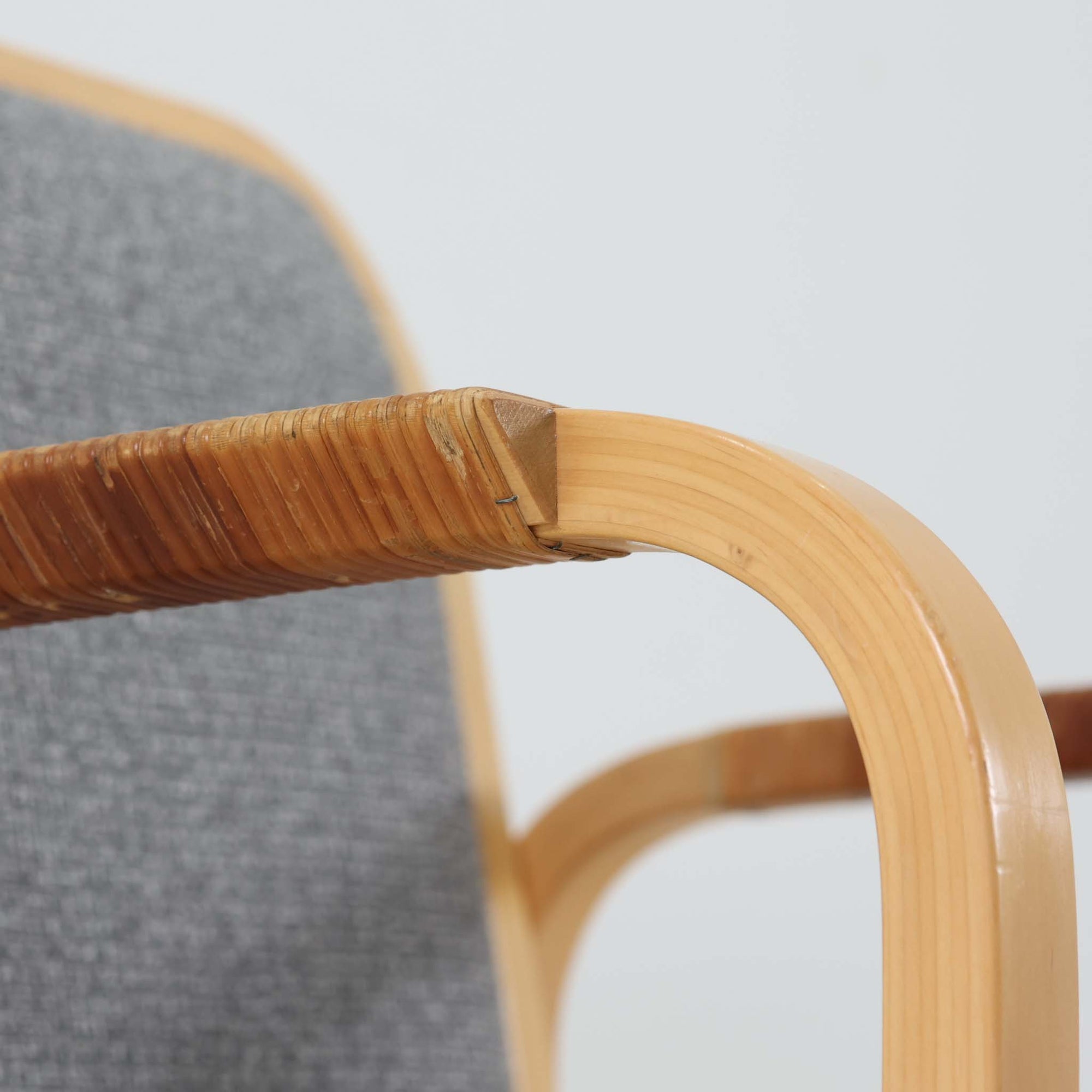 アルヴァ・アアルトが手掛け、アルテックより製作されたモデルE45のアームチェアは、積層バーチ材による滑らかなフレームと、アーム上部に施されたラタン巻きが特徴的な北欧ビンテージの名作です。直線と曲線を巧みに組み合わせた構造は、視覚的な軽やかさと高い強度を両立し、背と座には張りのあるファブリックを用いることで、長時間でも快適な座り心地を実現しています。使い込むほどに木部の色味が深まり、素材の経年変化を楽しめる点も魅力で、ダイニングや書斎、公共空間まで幅広いシーンで活躍する一脚です。