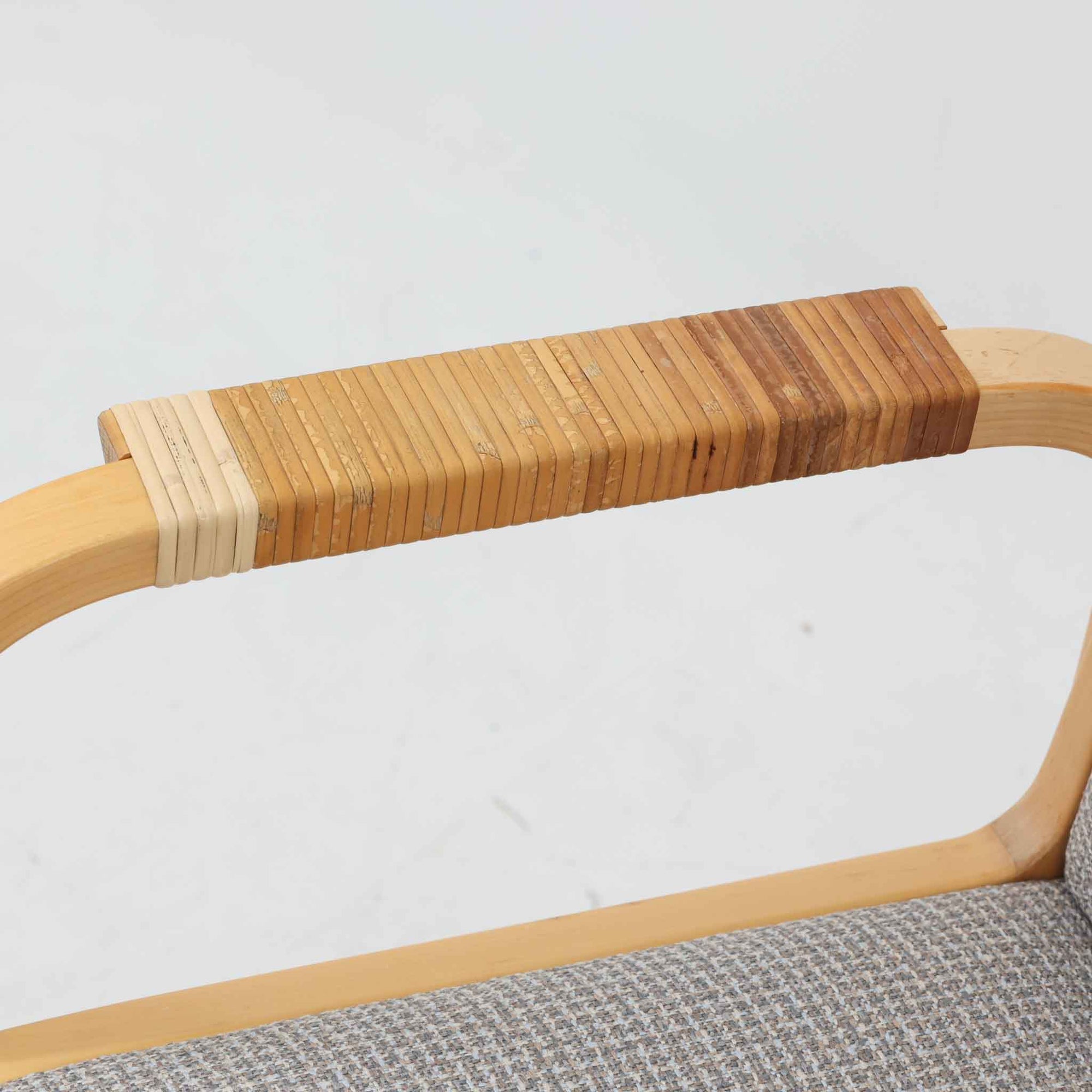 アルヴァ・アアルトが手掛け、アルテックより製作されたモデルE45のアームチェアは、積層バーチ材による滑らかなフレームと、アーム上部に施されたラタン巻きが特徴的な北欧ビンテージの名作です。直線と曲線を巧みに組み合わせた構造は、視覚的な軽やかさと高い強度を両立し、背と座には張りのあるファブリックを用いることで、長時間でも快適な座り心地を実現しています。使い込むほどに木部の色味が深まり、素材の経年変化を楽しめる点も魅力で、ダイニングや書斎、公共空間まで幅広いシーンで活躍する一脚です。