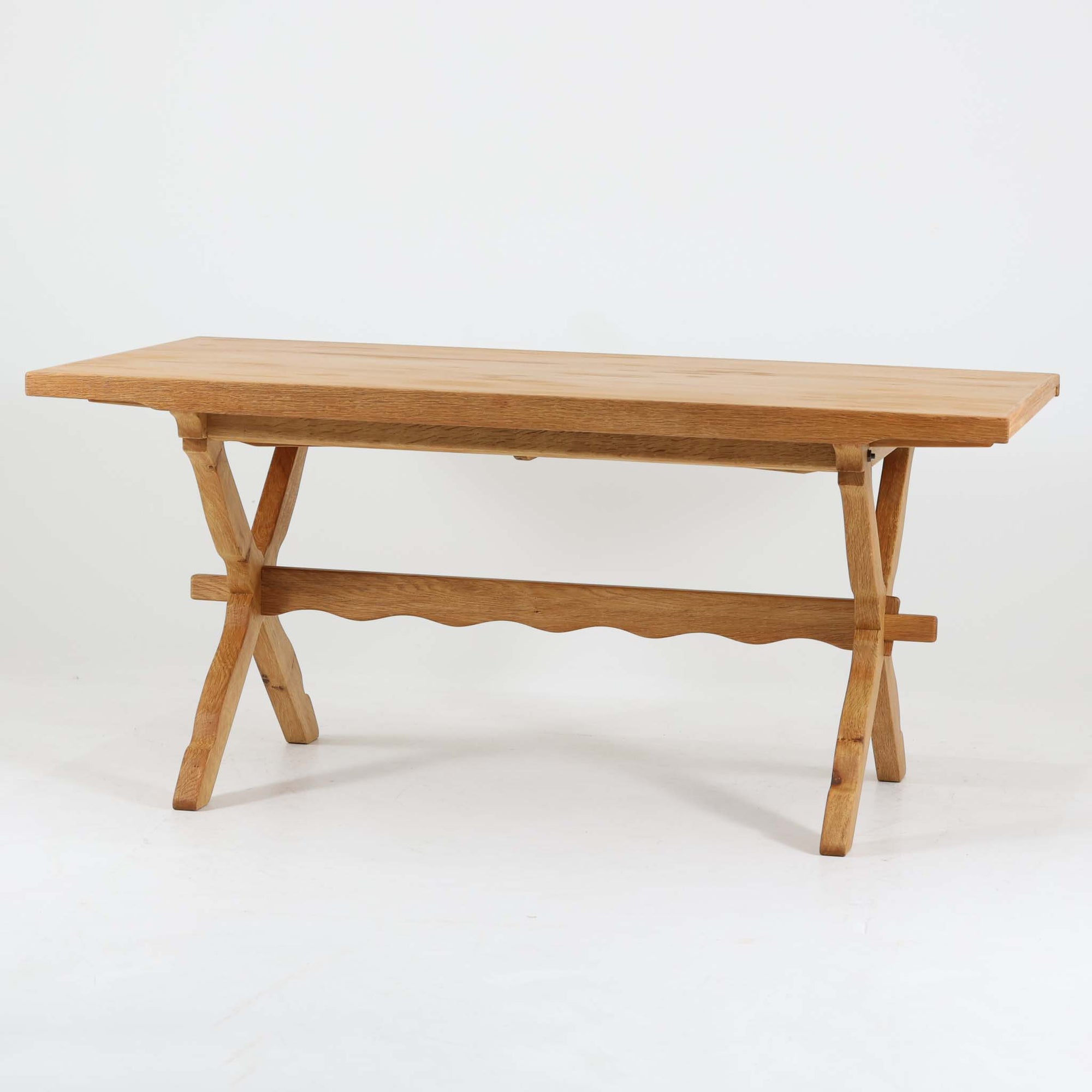 Henning Kjaernulfがデザインし、Nyrup Mobelfabrikが手掛けたエクステンションダイニングテーブルです。オーク材ならではの力強い木目と経年で深みを増した色艶が魅力で、X字状の脚部や波状に削り出された貫が北欧らしい素朴さと彫刻的な美しさを演出しています。左右の天板を引き出すことで幅251cmまで拡張可能な実用的構造で、日常使いから来客時まで幅広く活躍。重厚感がありながらも軽やかな意匠にまとめられた、希少性の高い北欧ビンテージ家具です。