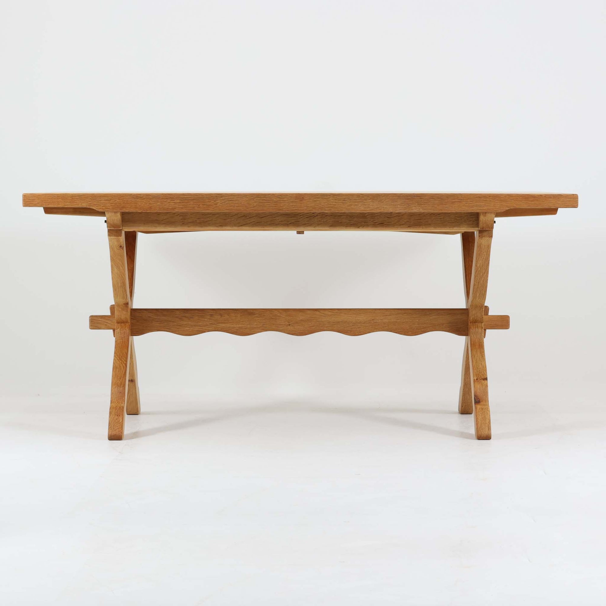 Henning Kjaernulfがデザインし、Nyrup Mobelfabrikが手掛けたエクステンションダイニングテーブルです。オーク材ならではの力強い木目と経年で深みを増した色艶が魅力で、X字状の脚部や波状に削り出された貫が北欧らしい素朴さと彫刻的な美しさを演出しています。左右の天板を引き出すことで幅251cmまで拡張可能な実用的構造で、日常使いから来客時まで幅広く活躍。重厚感がありながらも軽やかな意匠にまとめられた、希少性の高い北欧ビンテージ家具です。