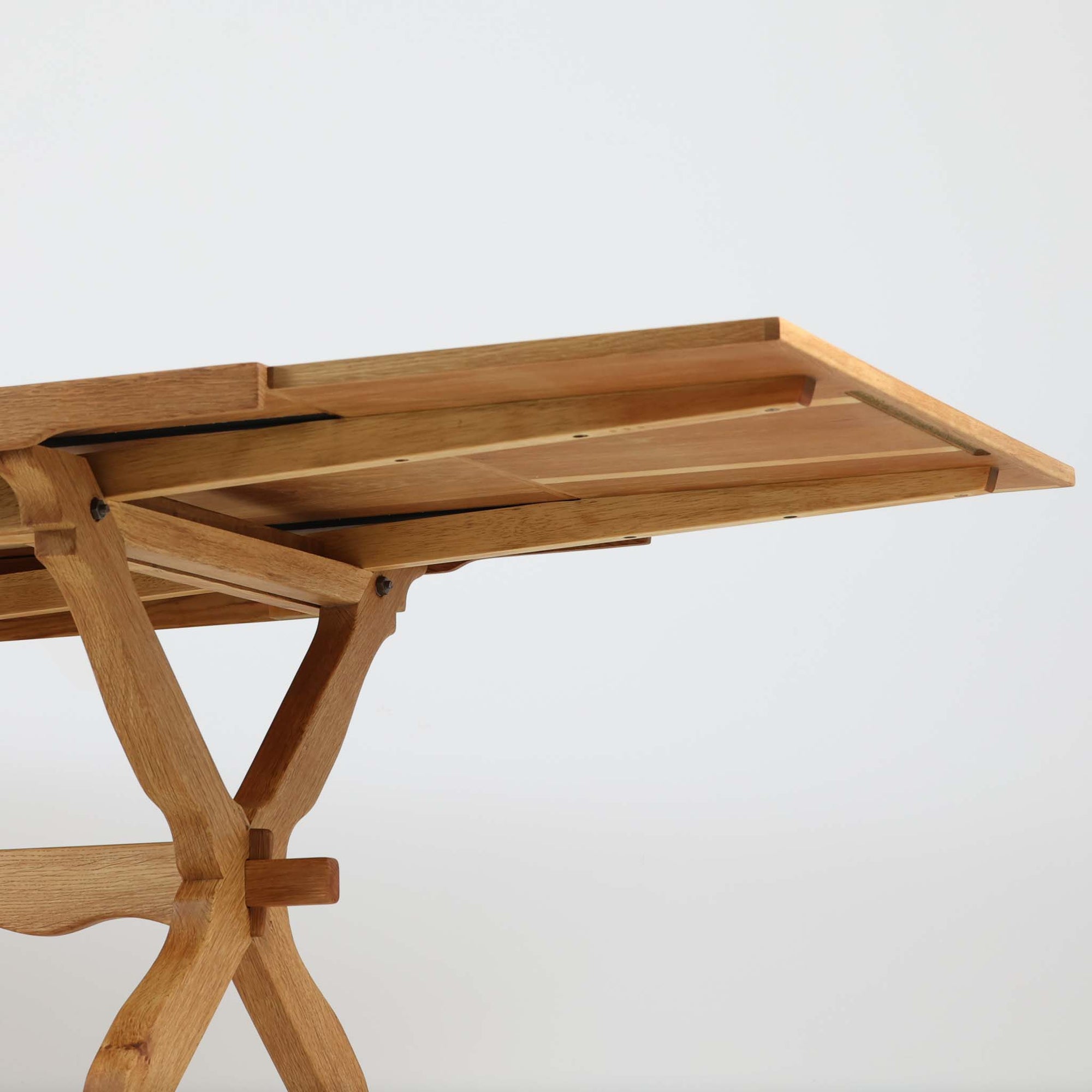 Henning Kjaernulfがデザインし、Nyrup Mobelfabrikが手掛けたエクステンションダイニングテーブルです。オーク材ならではの力強い木目と経年で深みを増した色艶が魅力で、X字状の脚部や波状に削り出された貫が北欧らしい素朴さと彫刻的な美しさを演出しています。左右の天板を引き出すことで幅251cmまで拡張可能な実用的構造で、日常使いから来客時まで幅広く活躍。重厚感がありながらも軽やかな意匠にまとめられた、希少性の高い北欧ビンテージ家具です。