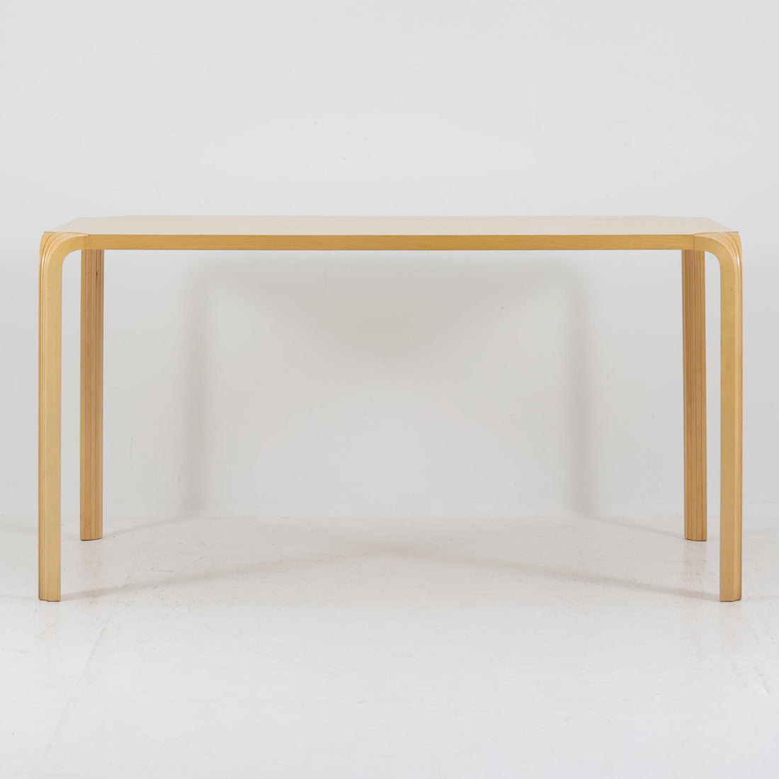 フィンランドを代表する建築家アルヴァ・アアルトによるデザイン、Artek社製の「X-leg」ダイニングテーブルです。素材には温かみのあるバーチ材を使用し、アアルトの象徴でもある積層合板による柔らかな曲線脚が特徴です。角のない優しいフォルムとシンプルな構造美が調和し、北欧デザインの真髄を感じさせます。経年によるバーチ材の飴色の風合いが美しく、空間に軽やかで穏やかな印象を与える一台です。