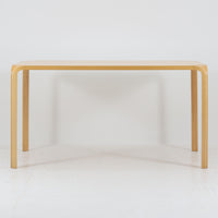 フィンランドを代表する建築家アルヴァ・アアルトによるデザイン、Artek社製の「X-leg」ダイニングテーブルです。素材には温かみのあるバーチ材を使用し、アアルトの象徴でもある積層合板による柔らかな曲線脚が特徴です。角のない優しいフォルムとシンプルな構造美が調和し、北欧デザインの真髄を感じさせます。経年によるバーチ材の飴色の風合いが美しく、空間に軽やかで穏やかな印象を与える一台です。