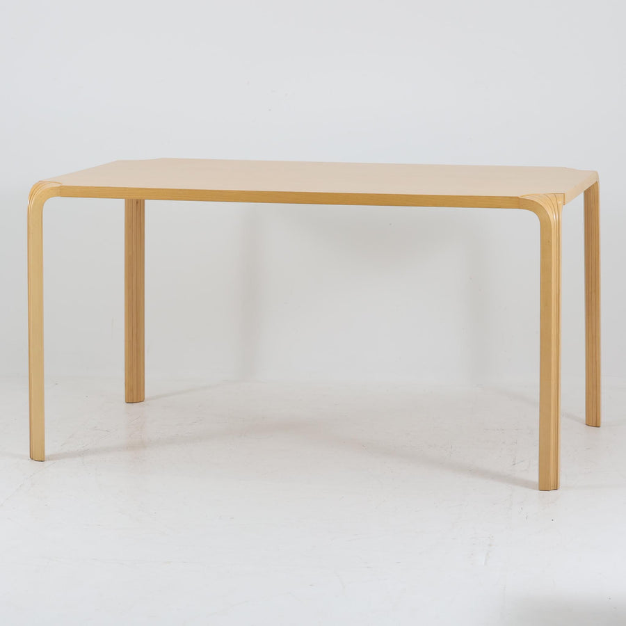 フィンランドを代表する建築家アルヴァ・アアルトによるデザイン、Artek社製の「X-leg」ダイニングテーブルです。素材には温かみのあるバーチ材を使用し、アアルトの象徴でもある積層合板による柔らかな曲線脚が特徴です。角のない優しいフォルムとシンプルな構造美が調和し、北欧デザインの真髄を感じさせます。経年によるバーチ材の飴色の風合いが美しく、空間に軽やかで穏やかな印象を与える一台です。