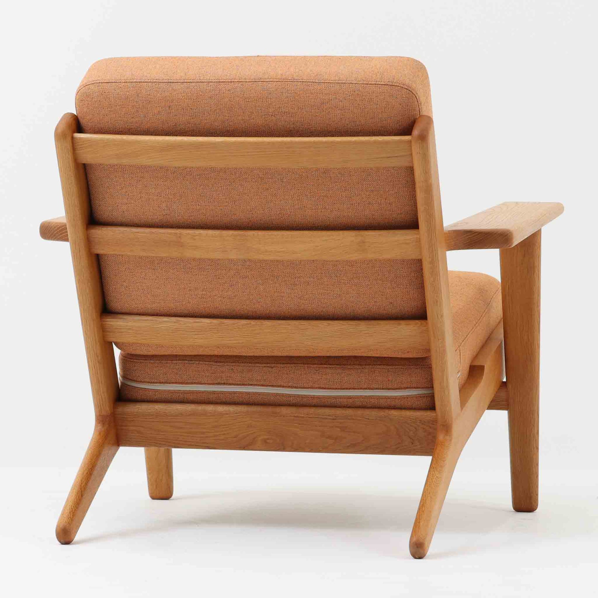 Hans J. Wegnerがデザインし、Getama社によって製作されたGE290は、構造の美しさと快適な座り心地を兼ね備えた北欧ビンテージを代表するシングルソファです。厚みのあるクッションと緩やかに傾斜した背もたれが身体を包み込み、自然と深いリラックス姿勢へと導きます。クッション内部にはビンテージ品ならではのスプリングが内包されており、しっかりとした弾力と安定感のある座り心地を生み出しています。オーク材のフレームは力強さと温かみを併せ持ち、アームから脚部にかけての造形にはウェグナーらしい彫刻的な魅力が感じられます。張地の落ち着いた色合いと、経年により深みを増した木部の表情が調和し、リビングや書斎で長く寄り添う一脚です。