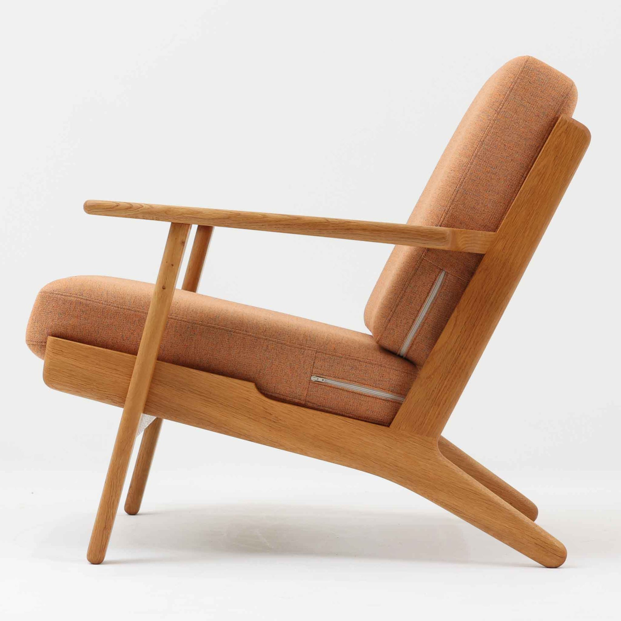 Hans J. Wegnerがデザインし、Getama社によって製作されたGE290は、構造の美しさと快適な座り心地を兼ね備えた北欧ビンテージを代表するシングルソファです。厚みのあるクッションと緩やかに傾斜した背もたれが身体を包み込み、自然と深いリラックス姿勢へと導きます。クッション内部にはビンテージ品ならではのスプリングが内包されており、しっかりとした弾力と安定感のある座り心地を生み出しています。オーク材のフレームは力強さと温かみを併せ持ち、アームから脚部にかけての造形にはウェグナーらしい彫刻的な魅力が感じられます。張地の落ち着いた色合いと、経年により深みを増した木部の表情が調和し、リビングや書斎で長く寄り添う一脚です。
