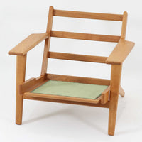 Hans J. Wegnerがデザインし、Getama社によって製作されたGE290は、構造の美しさと快適な座り心地を兼ね備えた北欧ビンテージを代表するシングルソファです。厚みのあるクッションと緩やかに傾斜した背もたれが身体を包み込み、自然と深いリラックス姿勢へと導きます。クッション内部にはビンテージ品ならではのスプリングが内包されており、しっかりとした弾力と安定感のある座り心地を生み出しています。オーク材のフレームは力強さと温かみを併せ持ち、アームから脚部にかけての造形にはウェグナーらしい彫刻的な魅力が感じられます。張地の落ち着いた色合いと、経年により深みを増した木部の表情が調和し、リビングや書斎で長く寄り添う一脚です。