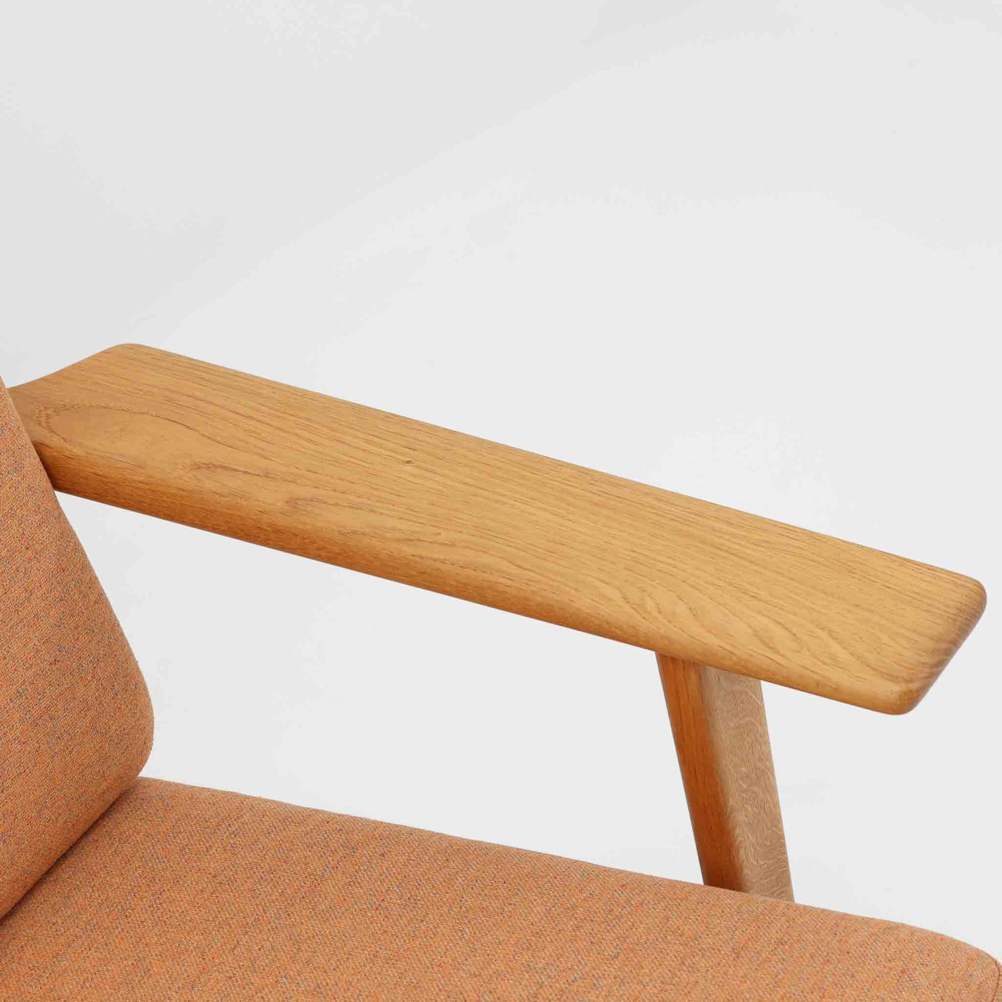 Hans J. Wegnerがデザインし、Getama社によって製作されたGE290は、構造の美しさと快適な座り心地を兼ね備えた北欧ビンテージを代表するシングルソファです。厚みのあるクッションと緩やかに傾斜した背もたれが身体を包み込み、自然と深いリラックス姿勢へと導きます。クッション内部にはビンテージ品ならではのスプリングが内包されており、しっかりとした弾力と安定感のある座り心地を生み出しています。オーク材のフレームは力強さと温かみを併せ持ち、アームから脚部にかけての造形にはウェグナーらしい彫刻的な魅力が感じられます。張地の落ち着いた色合いと、経年により深みを増した木部の表情が調和し、リビングや書斎で長く寄り添う一脚です。