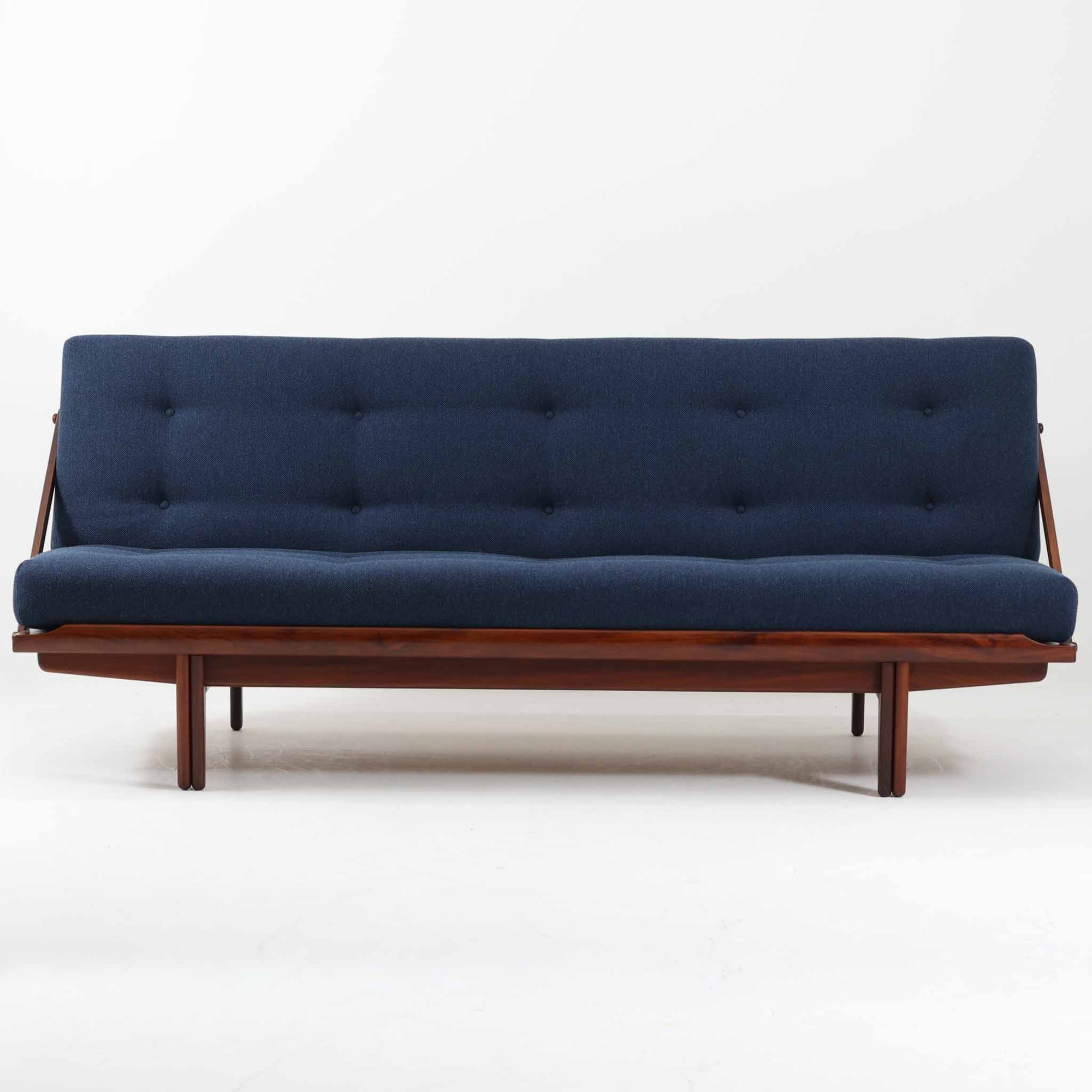 Poul M. Voltherによってデザインされたデイベッドは、機能性と美しさを兼ね備えたビンテージ家具です。ソファとしての使用はもちろん、背もたれを倒すことでリラックスできるベッドとしても使用でき、用途に応じて柔軟に活躍します。フレームにはアフロモシア材が使用されており、深みのある木目と上質な質感が空間に落ち着いた存在感を与えます。アフロモシア材仕様のモデルは流通数が少なく、希少性の高い点も魅力のひとつです。スラット構造による安定感のあるフレームに加え、クッション内部にはスプリングが内包されており、快適な座り心地と寝心地を提供してくれる一台です。