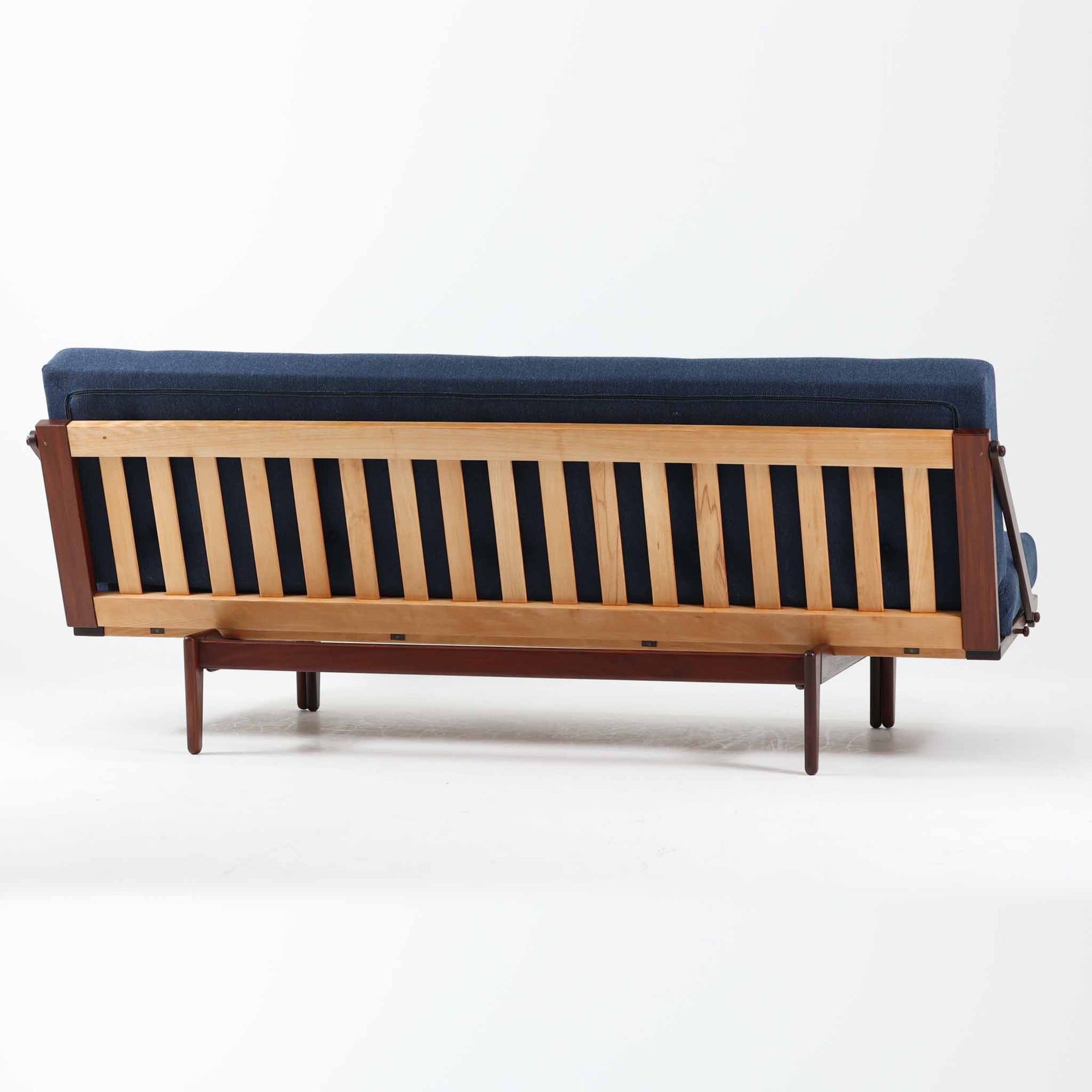 Poul M. Voltherによってデザインされたデイベッドは、機能性と美しさを兼ね備えたビンテージ家具です。ソファとしての使用はもちろん、背もたれを倒すことでリラックスできるベッドとしても使用でき、用途に応じて柔軟に活躍します。フレームにはアフロモシア材が使用されており、深みのある木目と上質な質感が空間に落ち着いた存在感を与えます。アフロモシア材仕様のモデルは流通数が少なく、希少性の高い点も魅力のひとつです。スラット構造による安定感のあるフレームに加え、クッション内部にはスプリングが内包されており、快適な座り心地と寝心地を提供してくれる一台です。