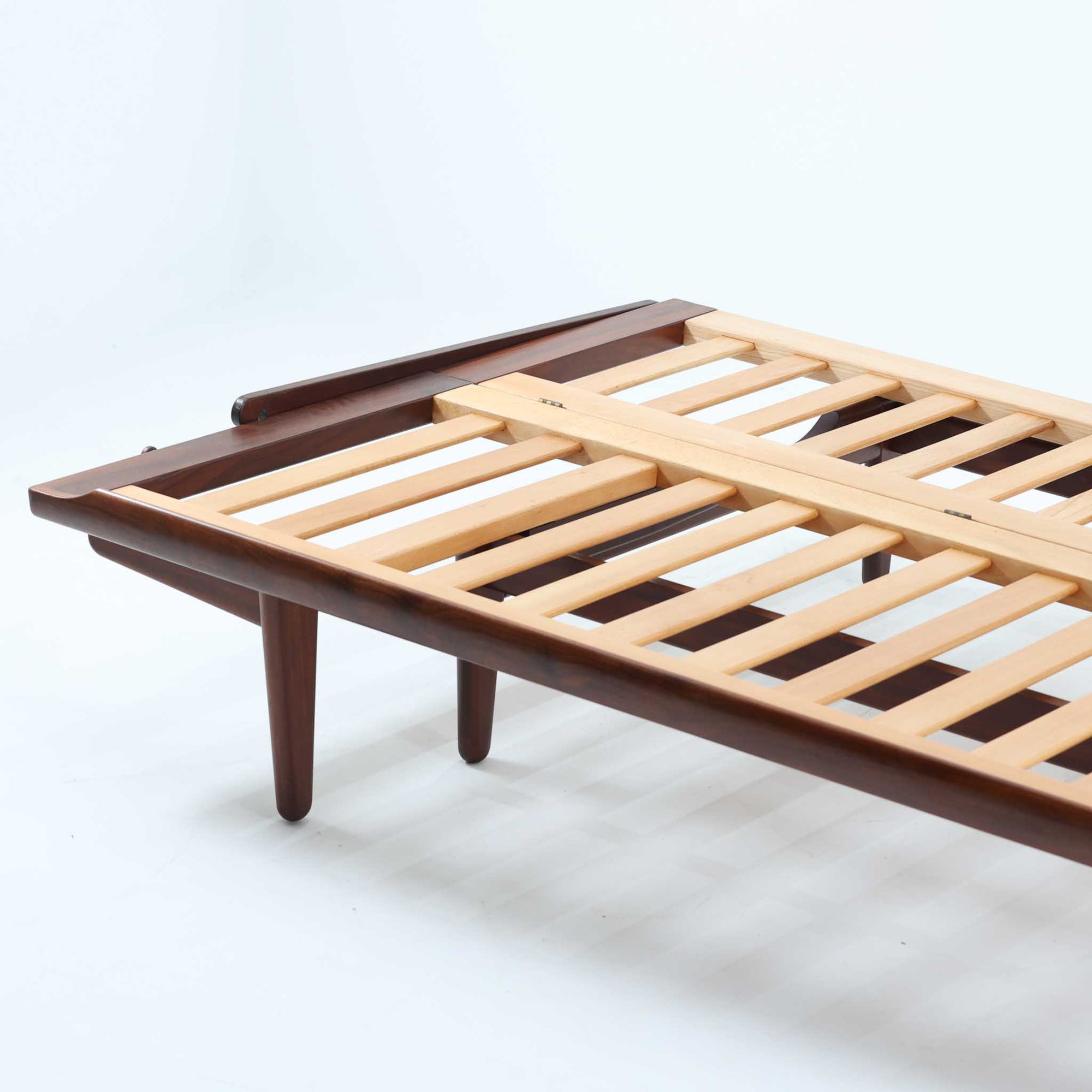 Poul M. Voltherによってデザインされたデイベッドは、機能性と美しさを兼ね備えたビンテージ家具です。ソファとしての使用はもちろん、背もたれを倒すことでリラックスできるベッドとしても使用でき、用途に応じて柔軟に活躍します。フレームにはアフロモシア材が使用されており、深みのある木目と上質な質感が空間に落ち着いた存在感を与えます。アフロモシア材仕様のモデルは流通数が少なく、希少性の高い点も魅力のひとつです。スラット構造による安定感のあるフレームに加え、クッション内部にはスプリングが内包されており、快適な座り心地と寝心地を提供してくれる一台です。