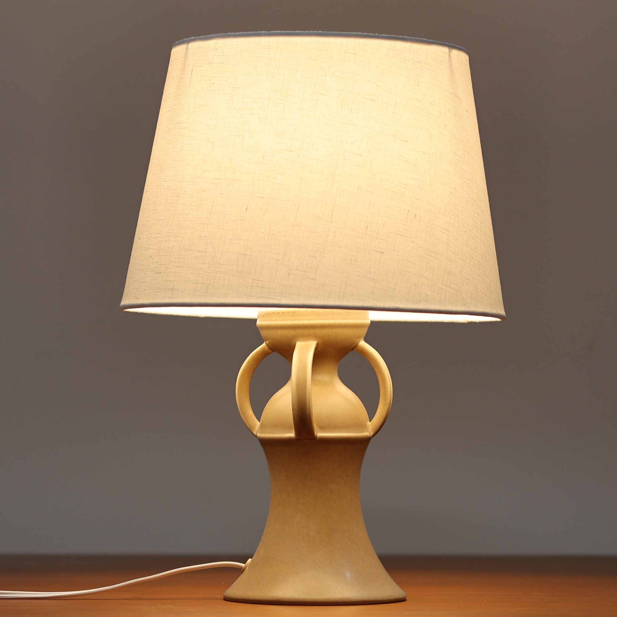 1993年にLe Klint創業50周年を記念して制作された、限定モデルのテーブルランプ「309」。ベースにはボーンホルム島の名門陶器工房Soholm（スーホルム）製のストーンウェアを採用し、シェードはLe Klint社製ではありませんが、新品のリネン製プリーツシェードを合わせており、クラシカルな佇まいと柔らかな光を演出します。北欧らしい温かみと洗練された存在感を持ち、ベッドサイドやリビングのアクセントとして取り入れやすい一灯です。ランプ底面には限定番号（No.0754）が刻まれており、コレクターズアイテムとしても価値ある一品です。