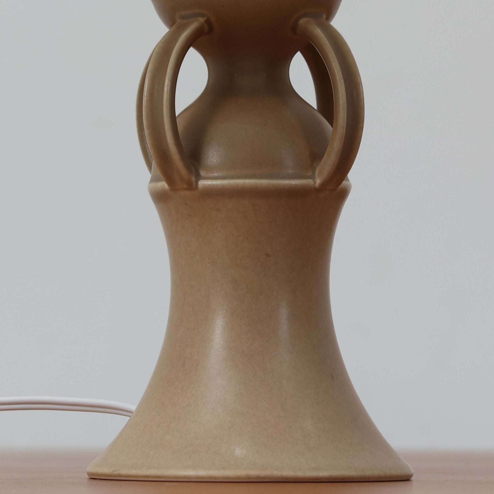 1993年にLe Klint創業50周年を記念して制作された、限定モデルのテーブルランプ「309」。ベースにはボーンホルム島の名門陶器工房Soholm（スーホルム）製のストーンウェアを採用し、シェードはLe Klint社製ではありませんが、新品のリネン製プリーツシェードを合わせており、クラシカルな佇まいと柔らかな光を演出します。北欧らしい温かみと洗練された存在感を持ち、ベッドサイドやリビングのアクセントとして取り入れやすい一灯です。ランプ底面には限定番号（No.0754）が刻まれており、コレクターズアイテムとしても価値ある一品です。